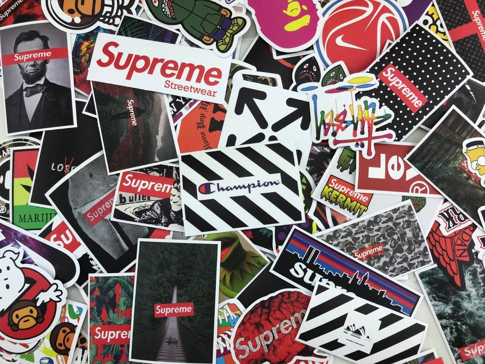Supreme紅黑風格美學貼紙 壁紙 — 一個混亂的拼貼畫，包含色彩繽紛的街頭服飾品牌貼紙，包括 Supreme Champion 和卡通人物，密集重疊。
