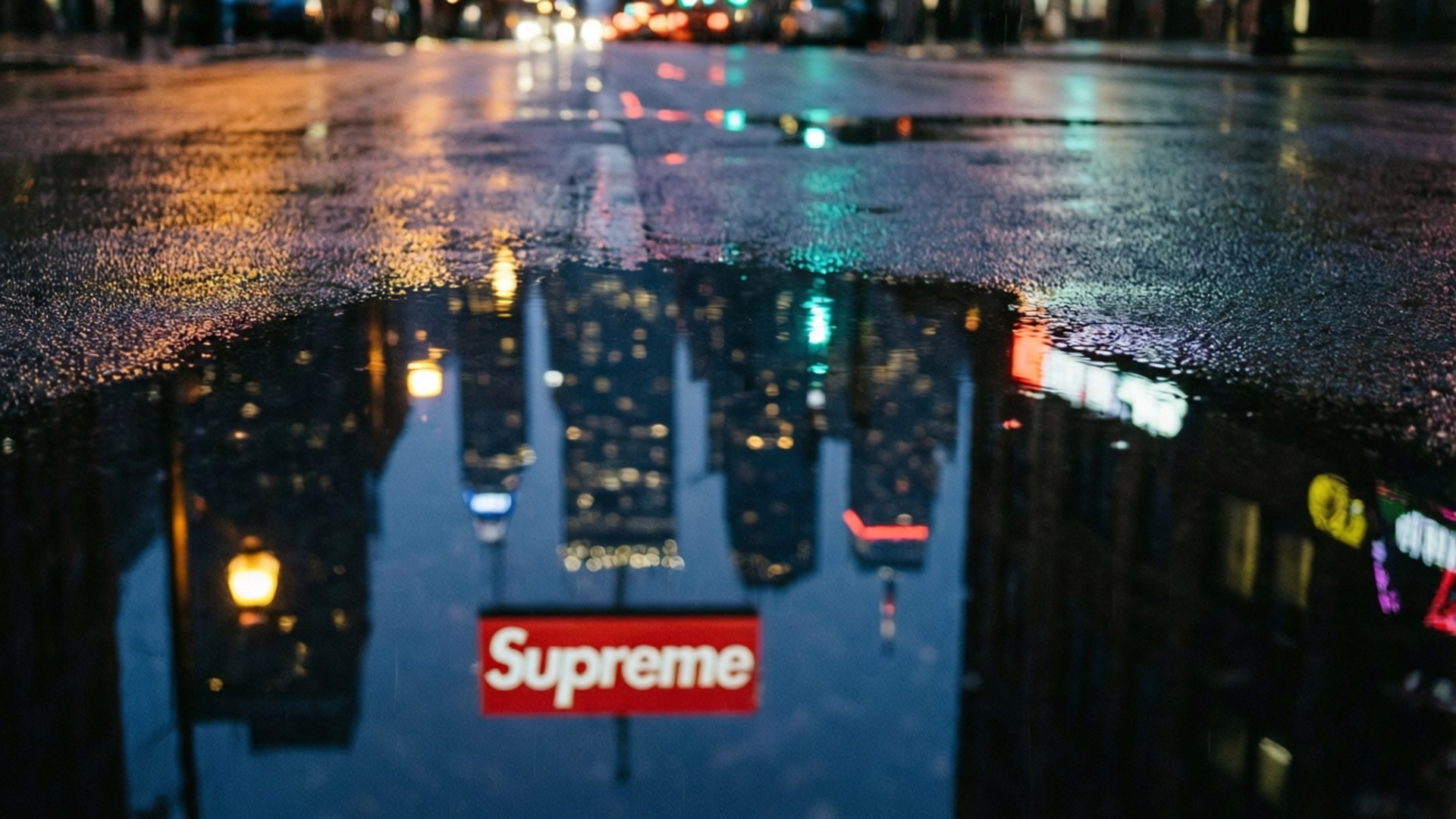 夜間城市街道水坑反射霓虹燈和紅色Supreme標誌。