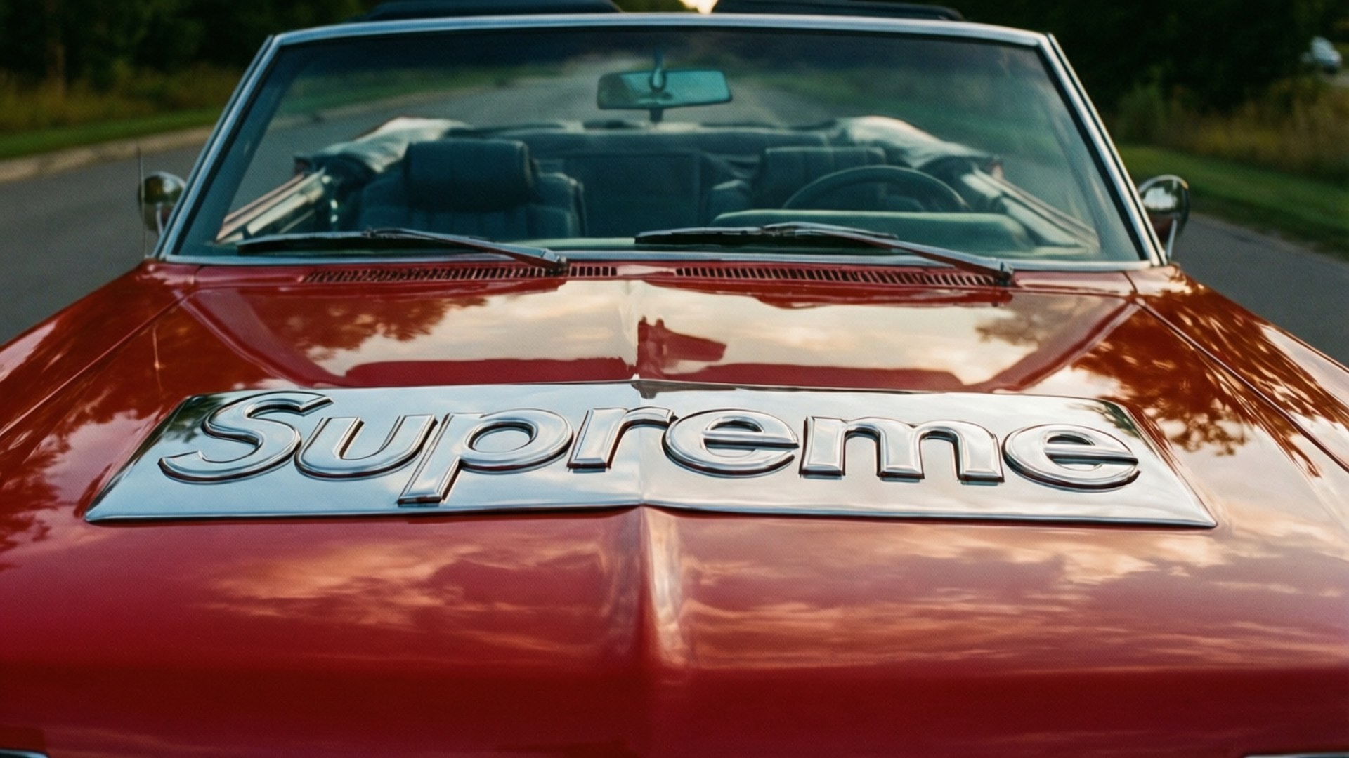 紅色敞篷車，引擎蓋上有鍍鉻Supreme標誌，反射天空雲朵