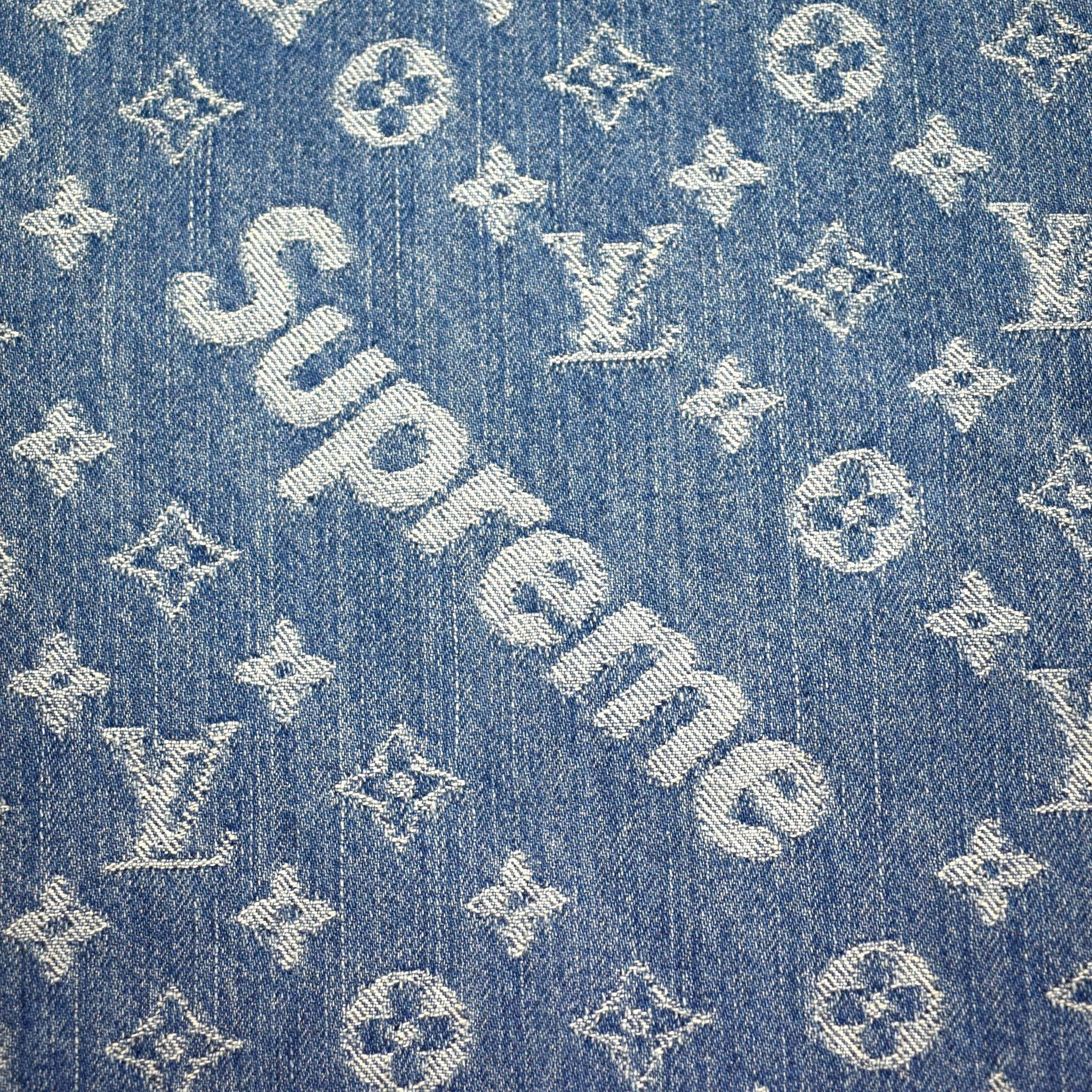 丹寧 Supreme x Louis Vuitton 設計布料 壁紙 — 藍色牛仔布料的特寫，帶有白色刺繡的 Louis Vuitton 字母組合和斜向的 Supreme 標誌。