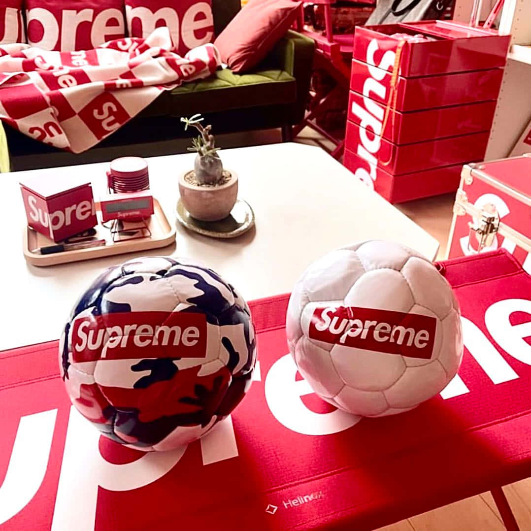 兩個 Supreme 足球在桌子上，背景有商品。
