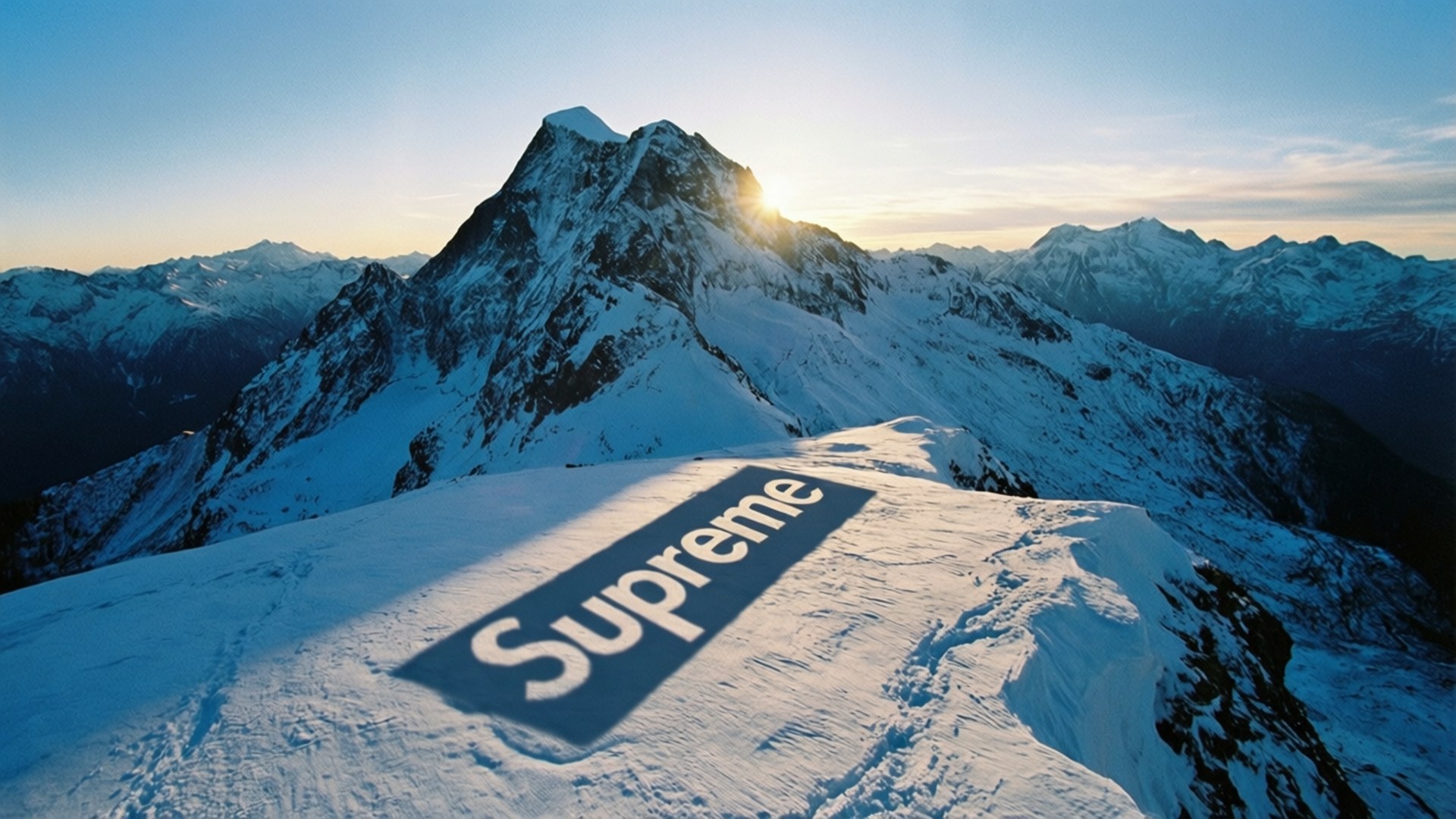 日出時分，山頂雪中嵌入的巨大Supreme標誌。
