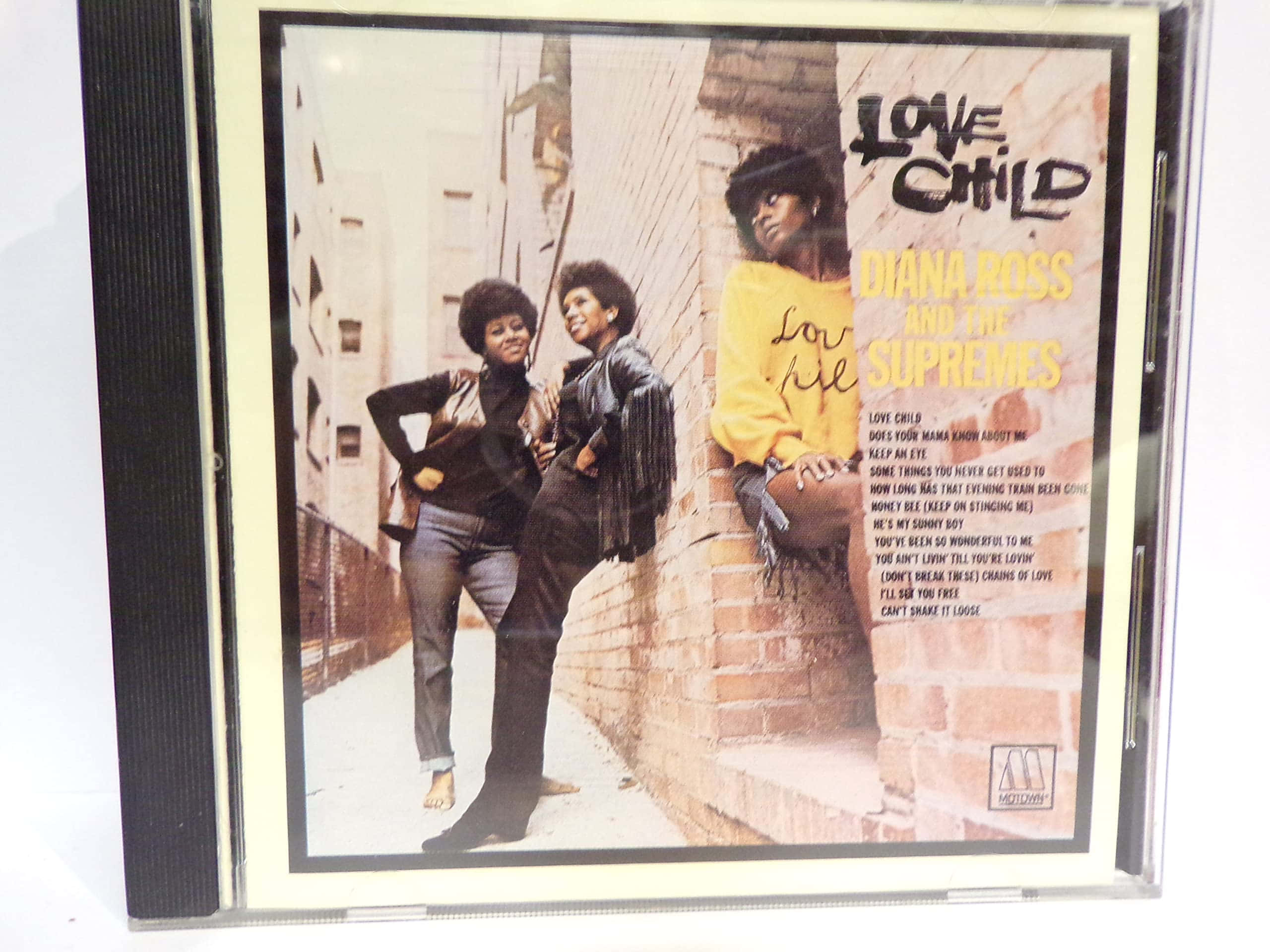 戴安娜·羅斯與 supremes《Love Child》專輯 壁紙 — 兩位穿著1970年代時尚的女性在城市的磚牆前自信地擺姿勢，並以CD盒框住。