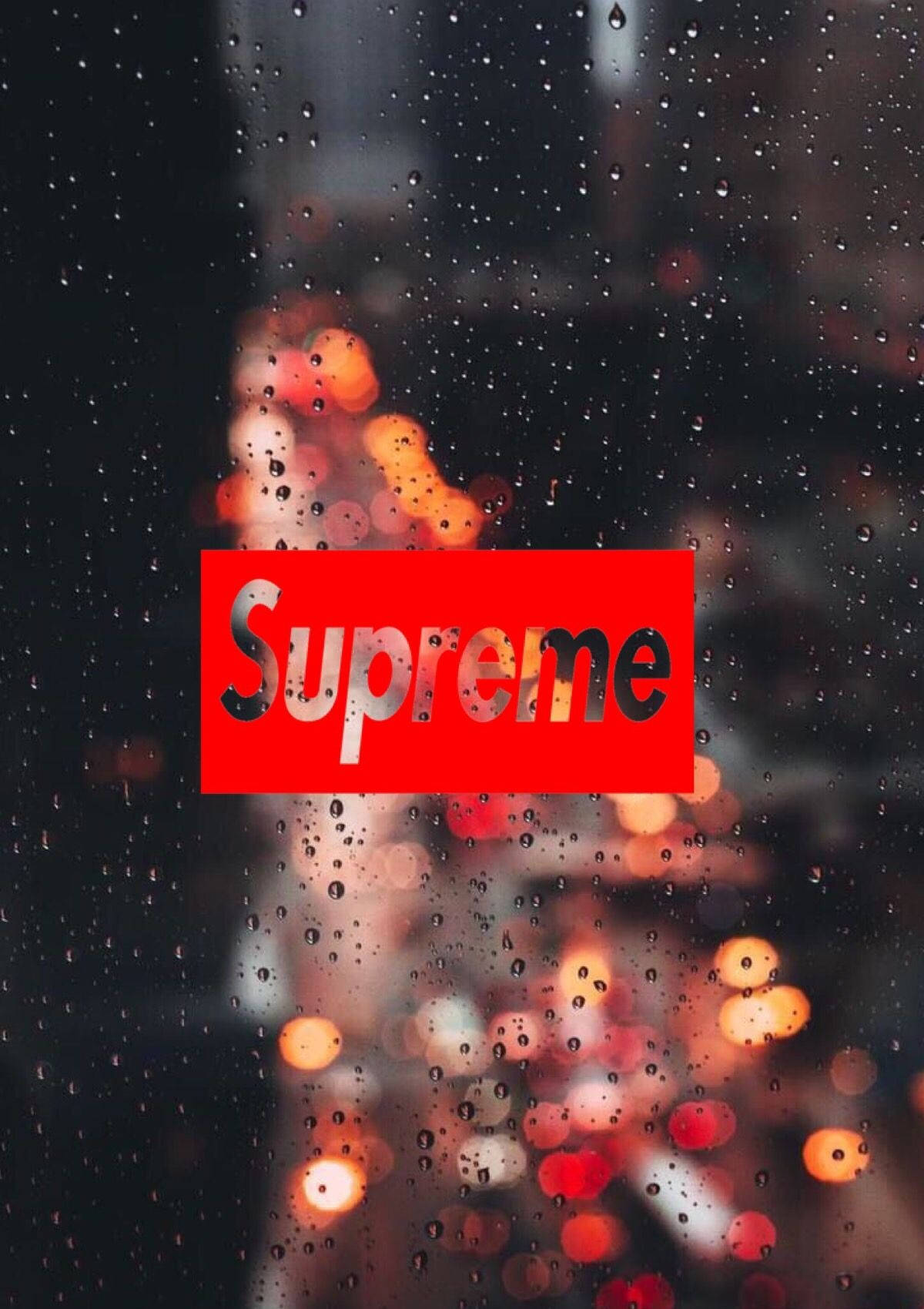 Supreme標誌與雨滴 壁紙 — 一個紅色Supreme標誌透過濺滿雨水的窗戶發光，背後是模糊的城市燈光。