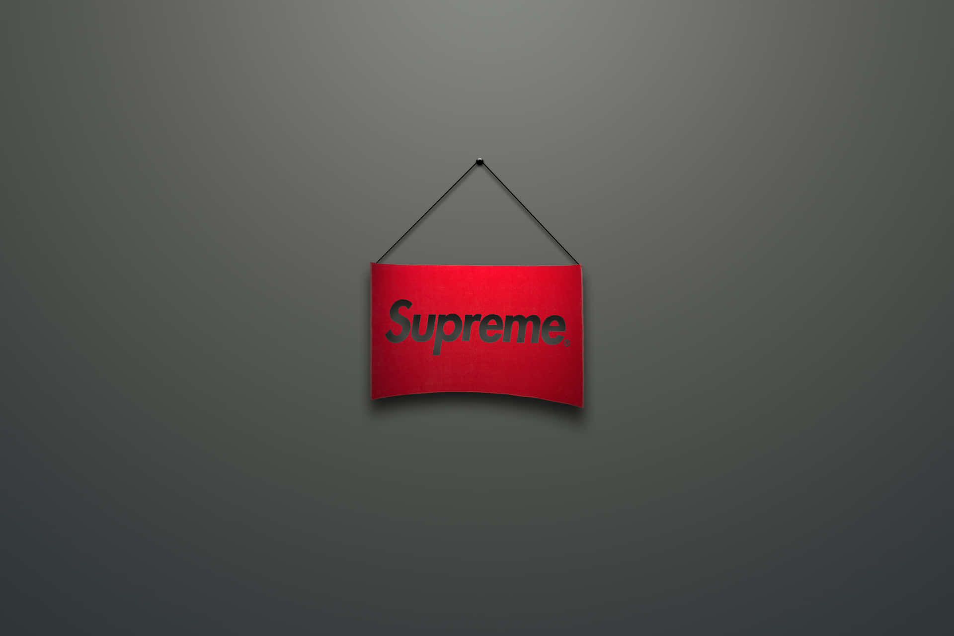 紅色Supreme標誌掛在灰色牆上。