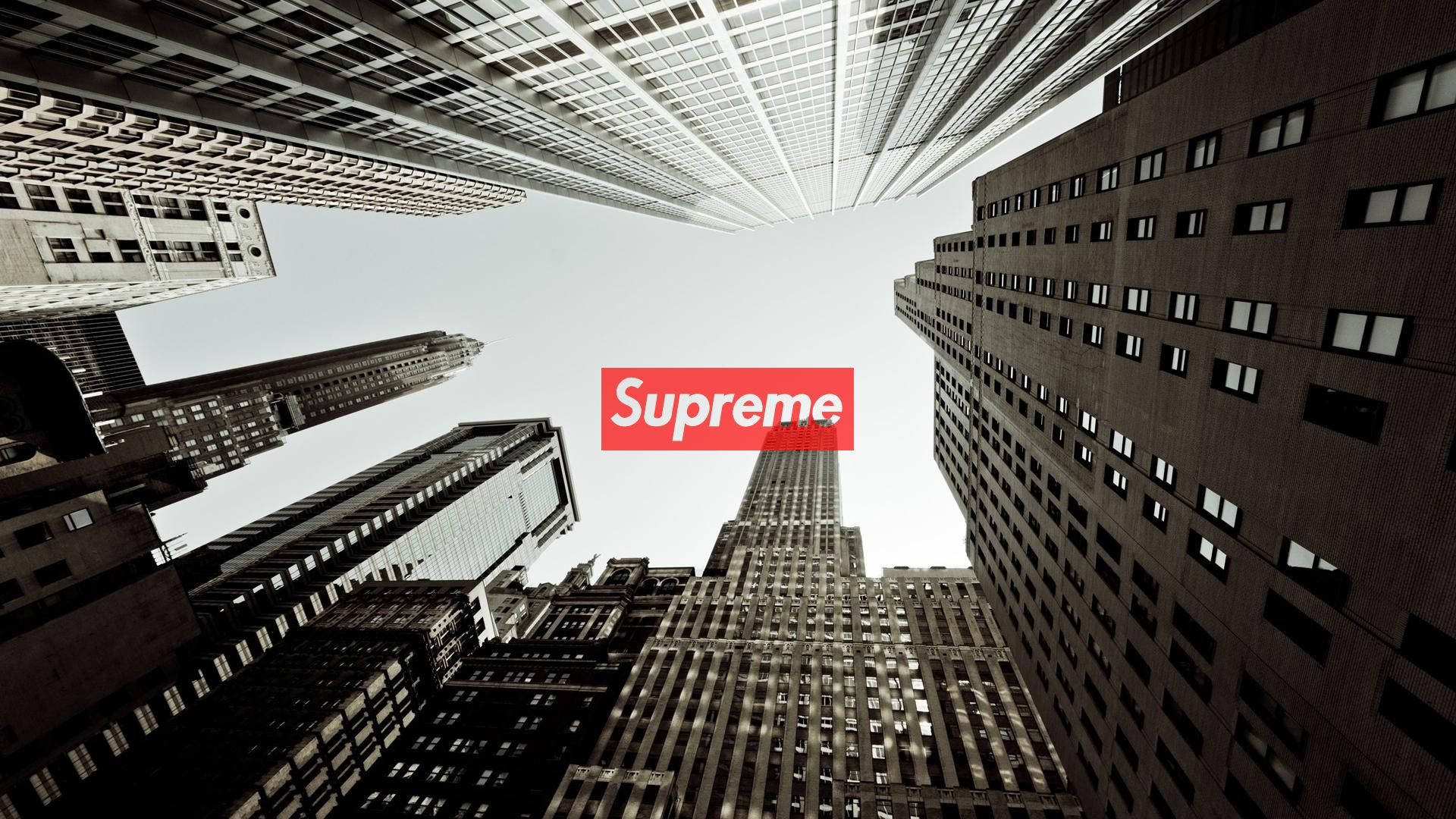 Supreme與高樓大廈 壁紙 — 低角度拍攝高聳摩天大樓匯聚向明亮天空，畫面中央有紅色 Supreme 標誌。