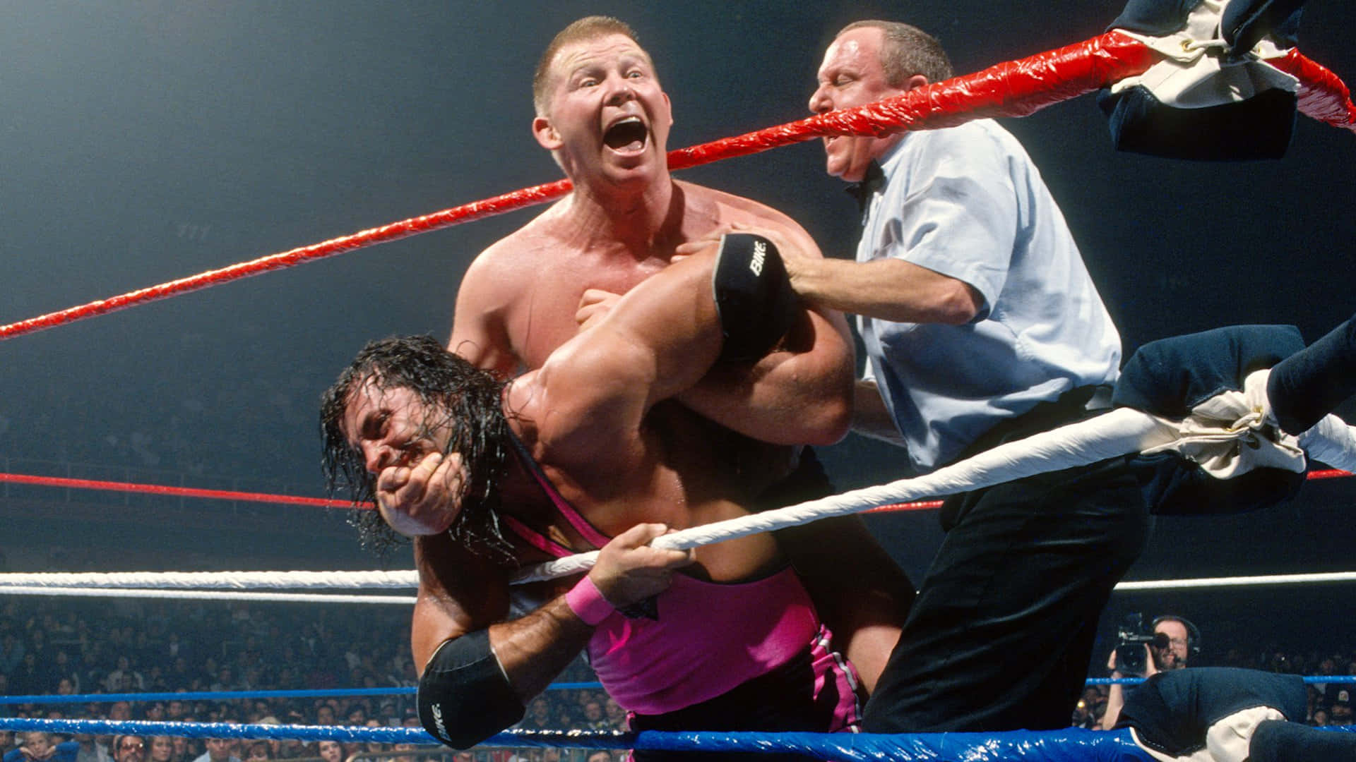 鮑勃·巴克蘭對戰布雷特·哈特 Survivor Series 1994 壁紙 — 兩名摔角手在擂台上激烈纏鬥，裁判在明亮的場館燈光下介入一場高風險比賽。