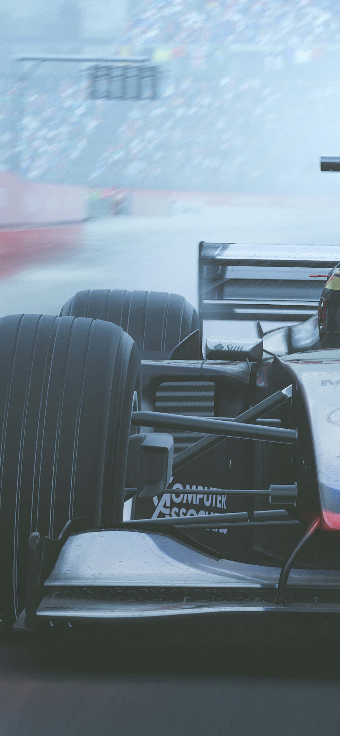 Suspension And Wheels Detail F1 2018 背景 壁紙 — 賽車尾部在賽道上疾馳的特寫，背景有模糊的觀眾。
