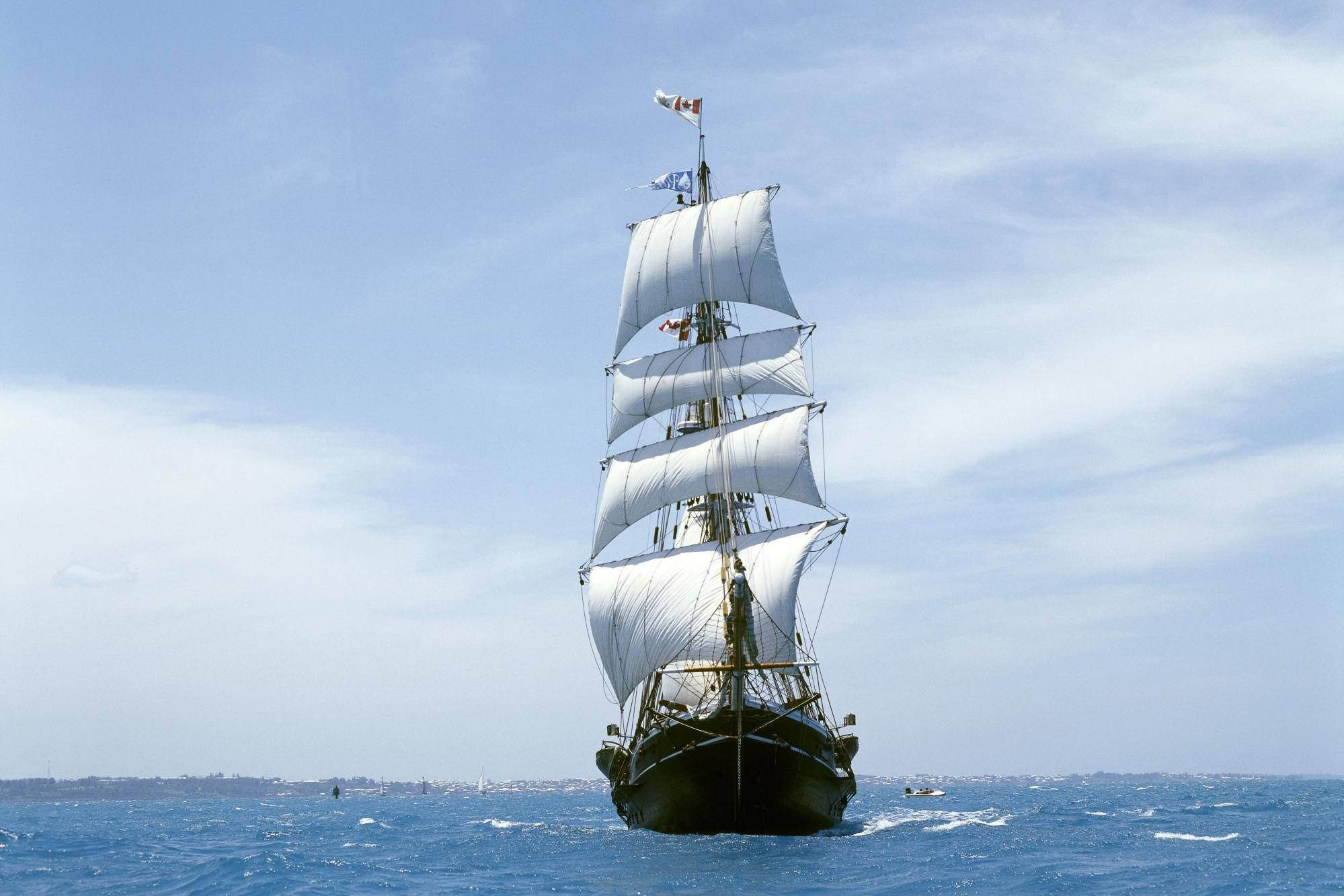 「SV Tenacious」帆船 壁紙 — 一艘高桅帆船鼓起白色風帆，在明亮的天空下劃過深藍色的海洋。