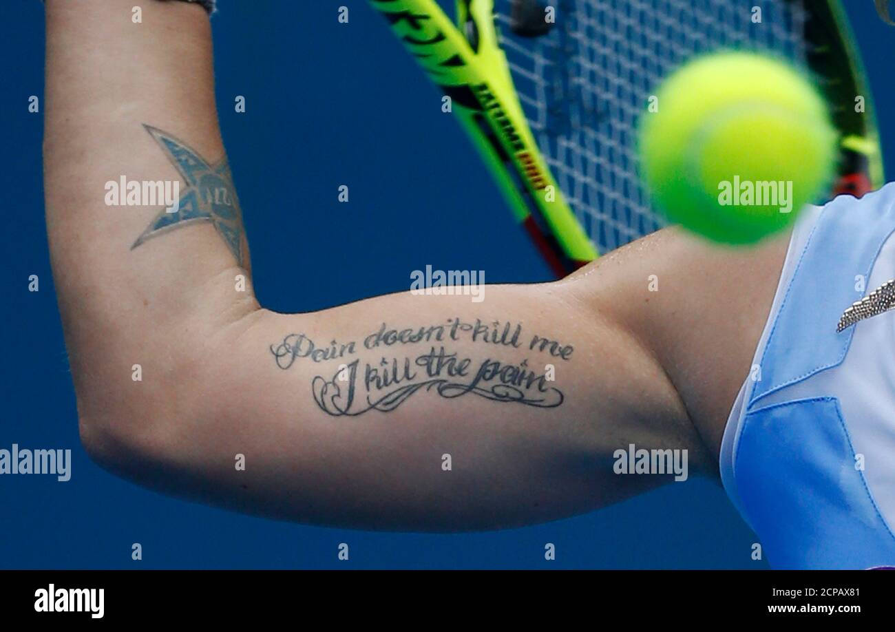 světlana_kuznetsova_手臂紋身特寫 壁紙 — 網球運動員有紋身的手臂揮動球拍的近距離特寫，模糊的黃色球在藍色球場背景上移動。