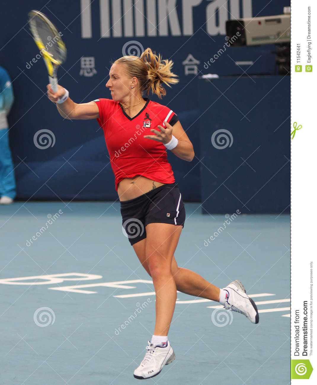 světlana_kuznetsova_揮拍擊球 壁紙 — 一位身穿紅色襯衫和黑色短褲的女網球手在藍色球場上揮拍擊球。