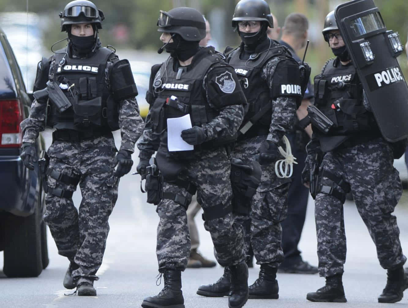 身穿戰術裝備的警察沿著街道行走。