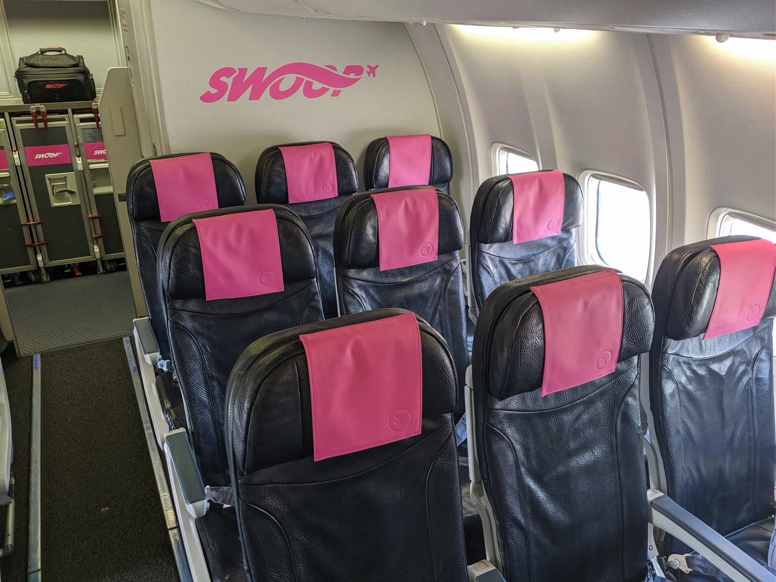 SWOOP 飛機內部，黑色座椅和粉紅色頭枕套。