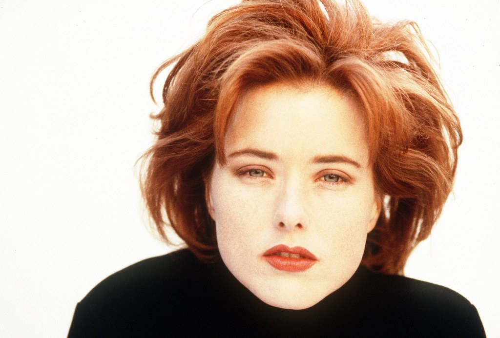 Téa Leoni 金色短髮 壁紙 — 一張女性特寫肖像，擁有火紅的頭髮和鮮豔的紅唇，背景為純白色。
