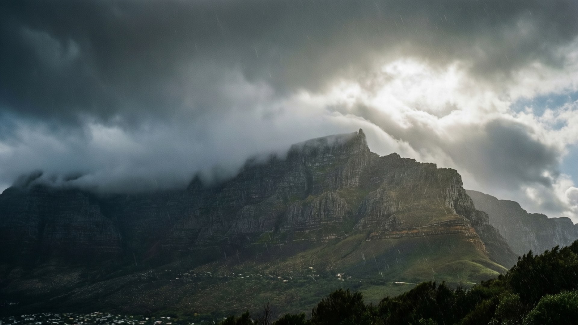 Table Mountain Storm 壁紙 — 戲劇性的山峰從暴風雲中浮現，陽光穿透雲層照耀在迷霧山谷之上。