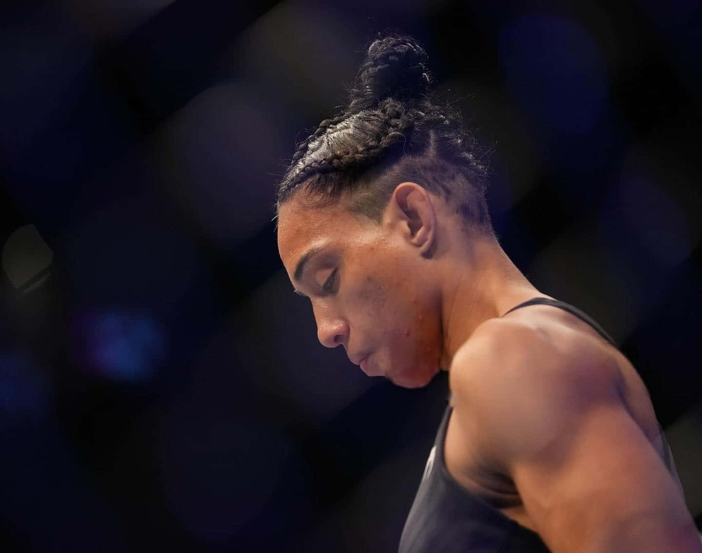 一位辮子女MMA拳手將頭靠在八角籠中。