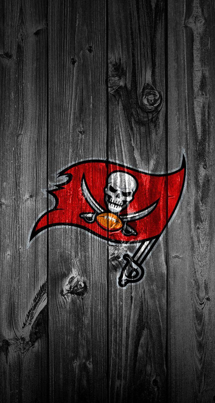 木紋 桌布 壁紙 — Tampa Bay Buccaneers 標誌，骷髏頭和足球在紅旗上，背景為風化的深色木板。