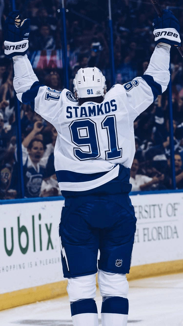 史蒂文·史塔科斯 Tampa Bay Lightning 賽場背影 壁紙 — 冰球運動員史丹高斯91號在冰上高舉雙臂慶祝，人群在玻璃後面歡呼。