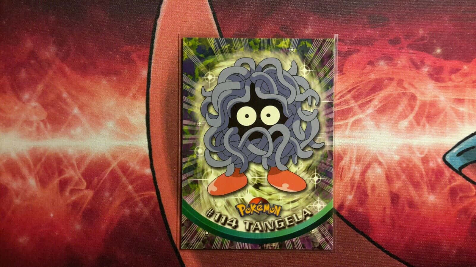 Tangela寶可夢卡牌 - 感受其力量！ 壁紙 — 一張寶可夢集換式卡牌，描繪藤蔓怪在火紅背景中散發綠色光芒。