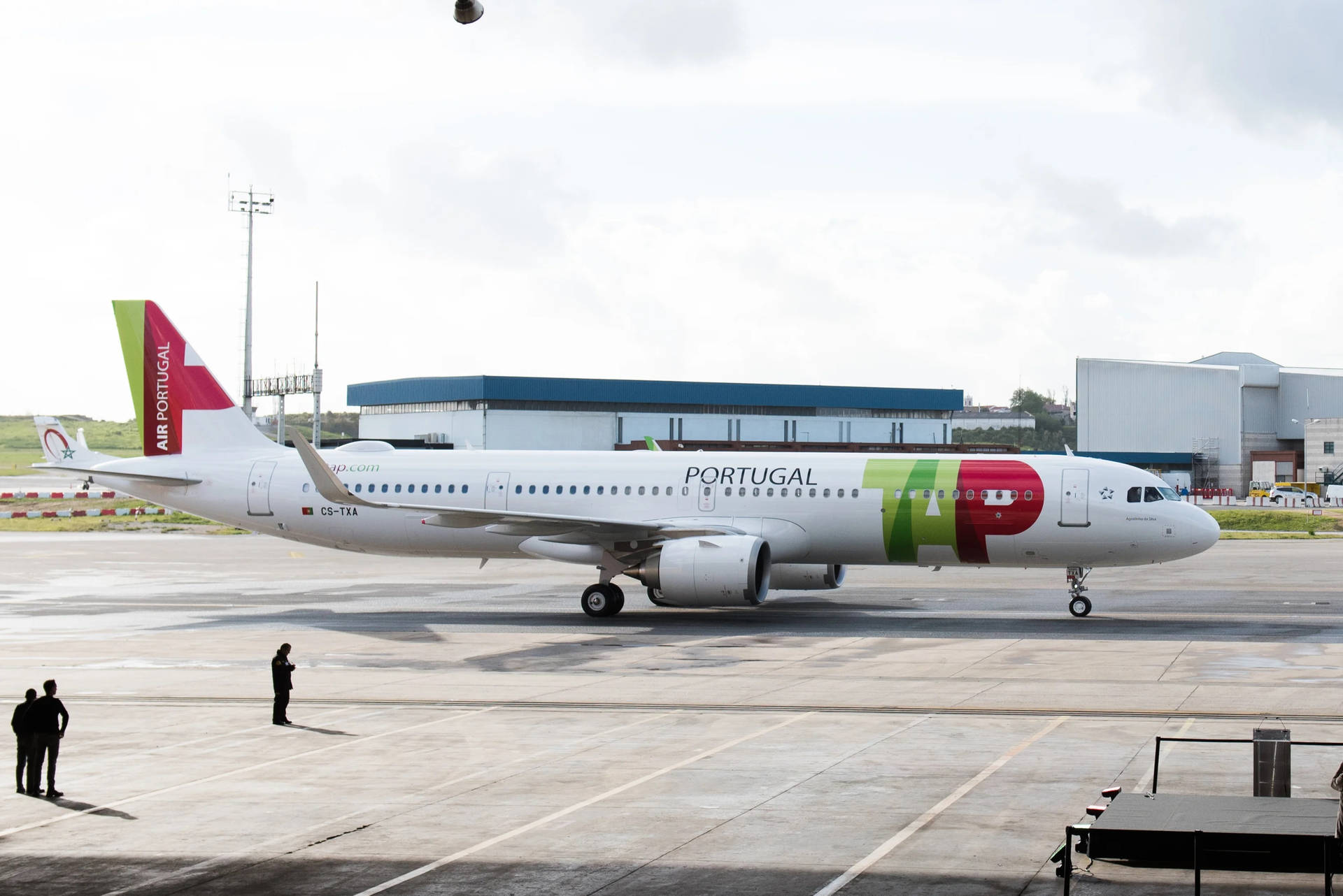 Air Portugal飛機喺濕滑停機坪上，附近有人，天空多雲
