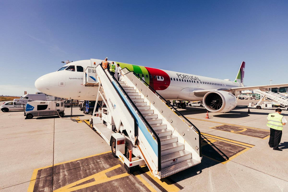 乘客在晴朗的機場停機坪上通過流動梯登上TAP Portugal飛機。