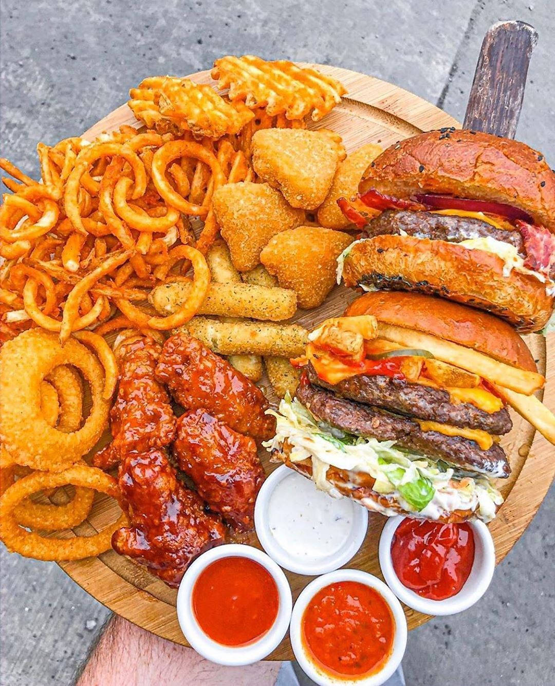 Tasty漢堡、雞翅、雞塊與薯條 壁紙 — 木盤上堆滿了美食漢堡、洋蔥圈、脆薯條和蜜糖雞翼，配上蘸醬。