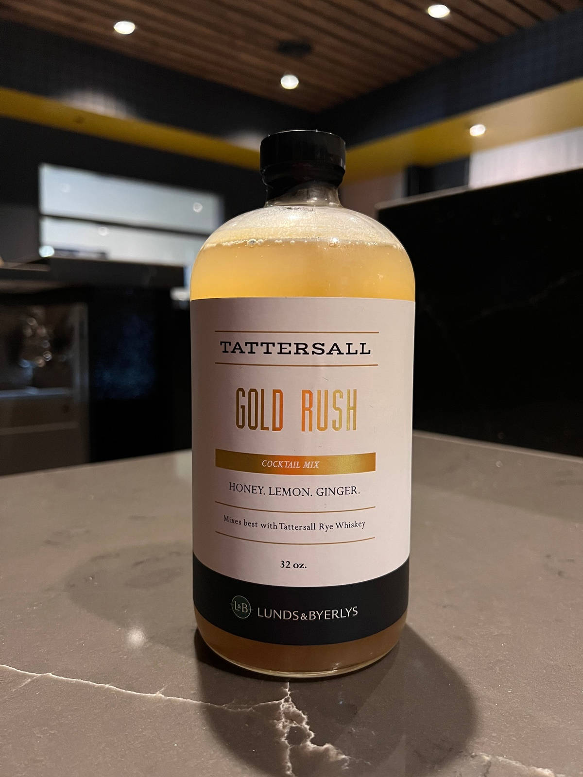 現代酒吧大理石檯面上的一瓶 Tattersall Gold Rush 雞尾酒調配液。