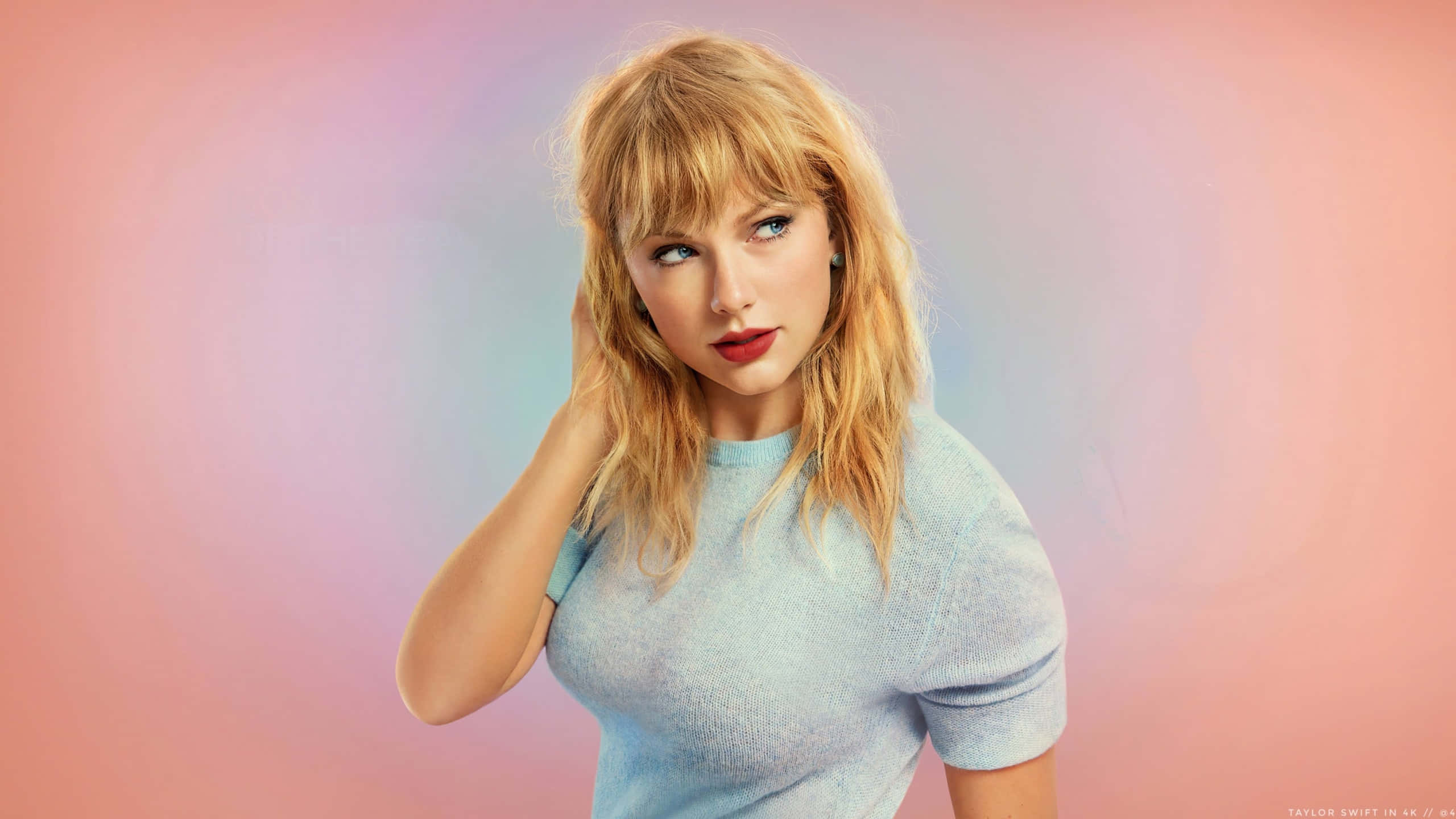 Taylor Swift Chromebook 桌布 壁紙 — Taylor Swift 自信地擺姿勢，身穿淺藍色毛衣，背景是柔和的粉藍漸變色。