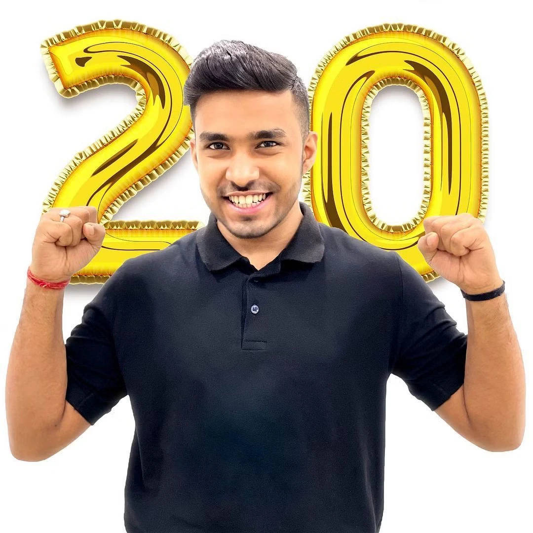 男人在金色20氣球後舉起拳頭慶祝。