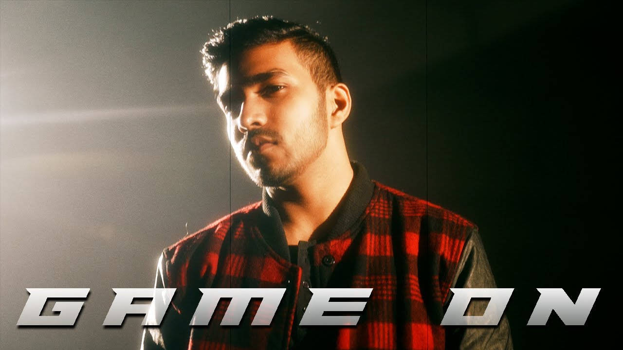 身穿紅色格仔外套的男子，帶有 'GAME ON' 文字，在戲劇性燈光下。
