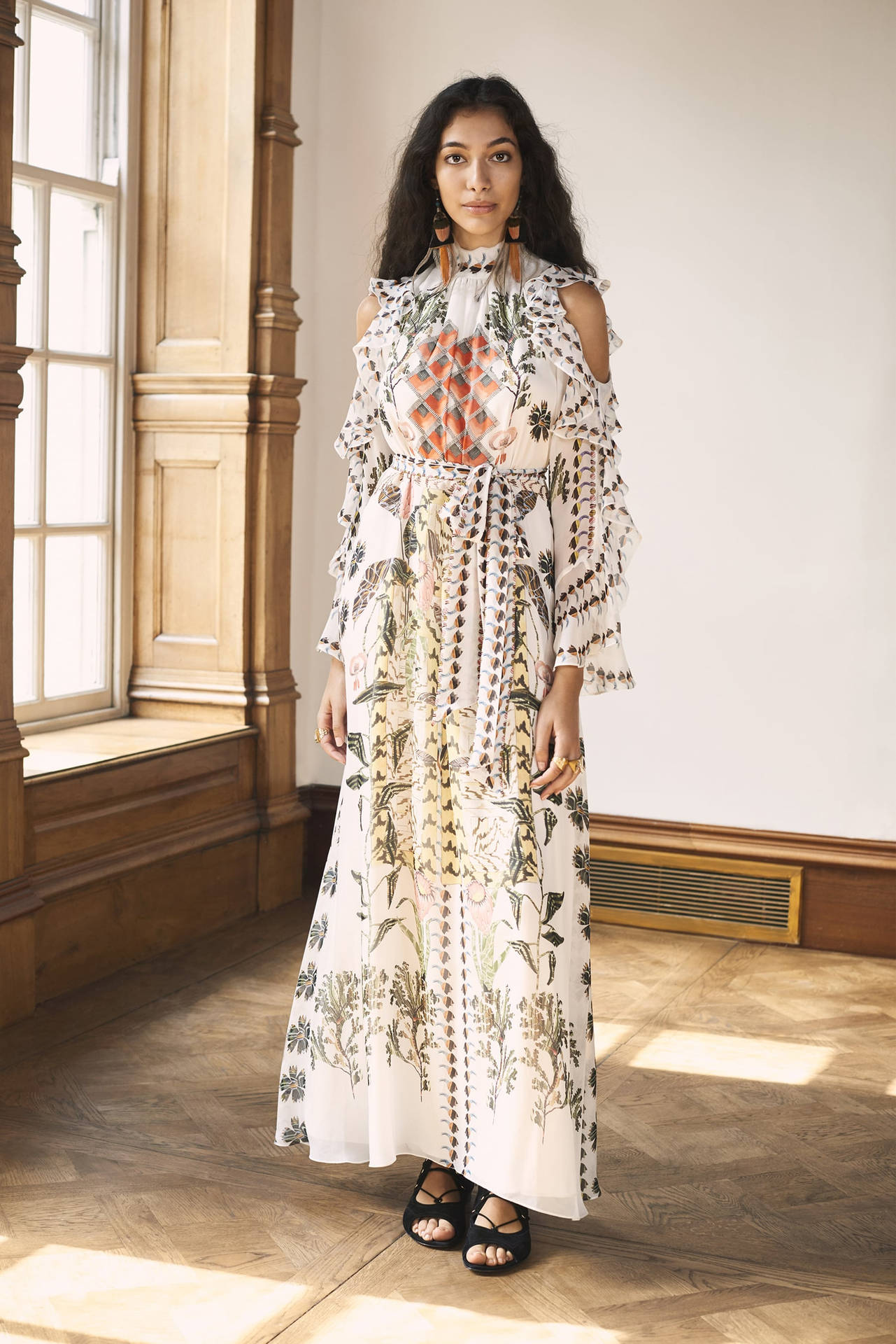 女性在陽光充足的木質房間中穿著花卉和幾何圖案連衣裙。
