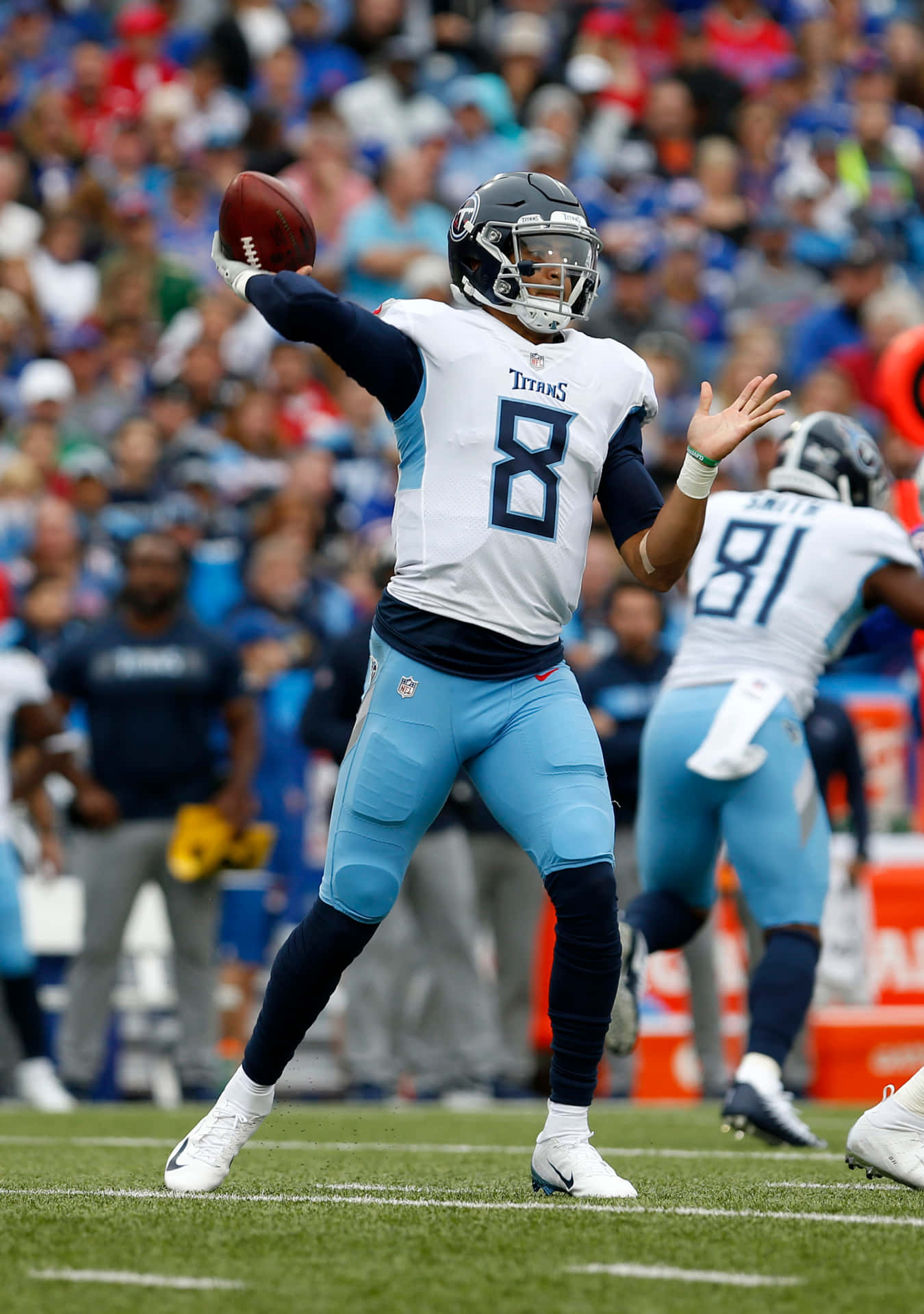  壁紙 — 一位身穿白色和淺藍色球衣的田納西泰坦四分衛在NFL日間比賽中擲出橄欖球，背景是模糊的人群。
