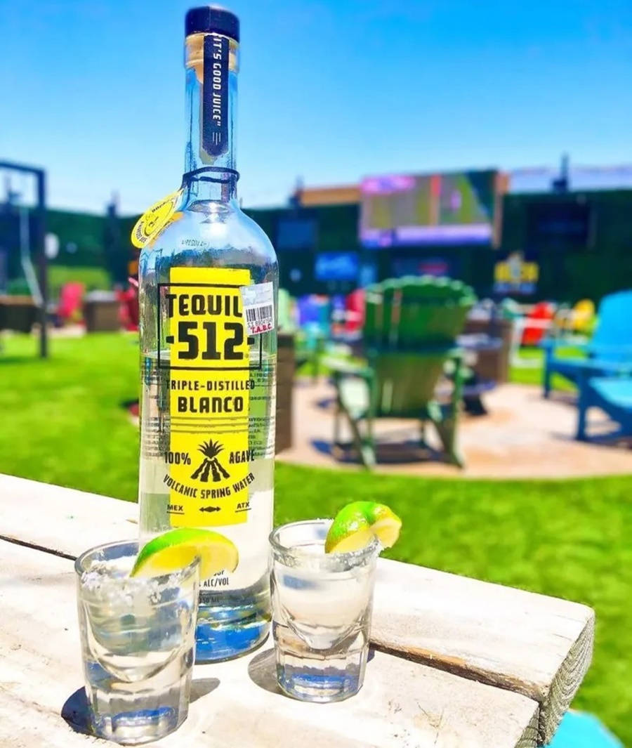 Tequila酒瓶和兩杯青檸烈酒在戶外木桌上。