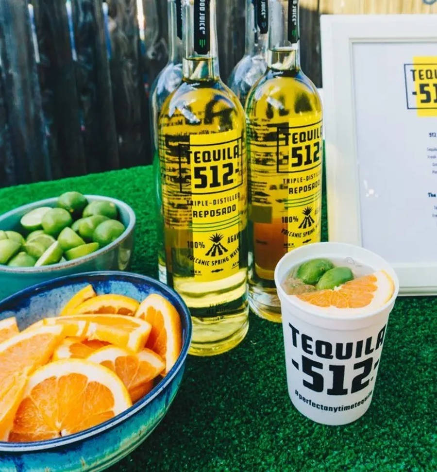 Tequila 512瓶子與青檸和橙片在綠色草地上。