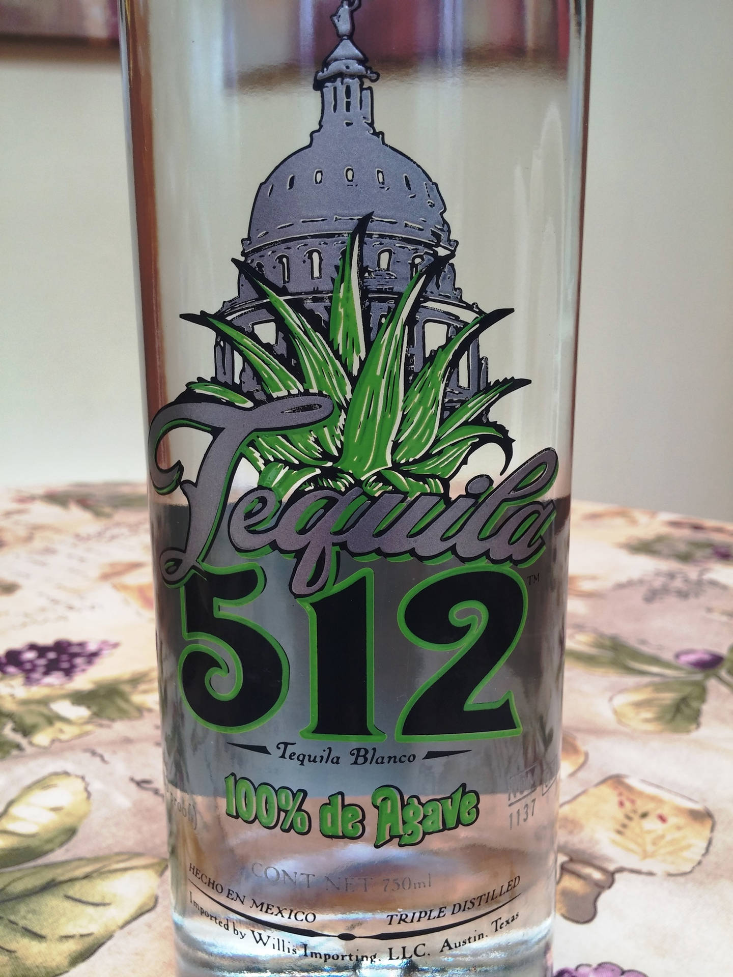 Tequila 512 Blanco 瓶子，帶有龍舌蘭和國會大廈設計，放在花卉桌布上。