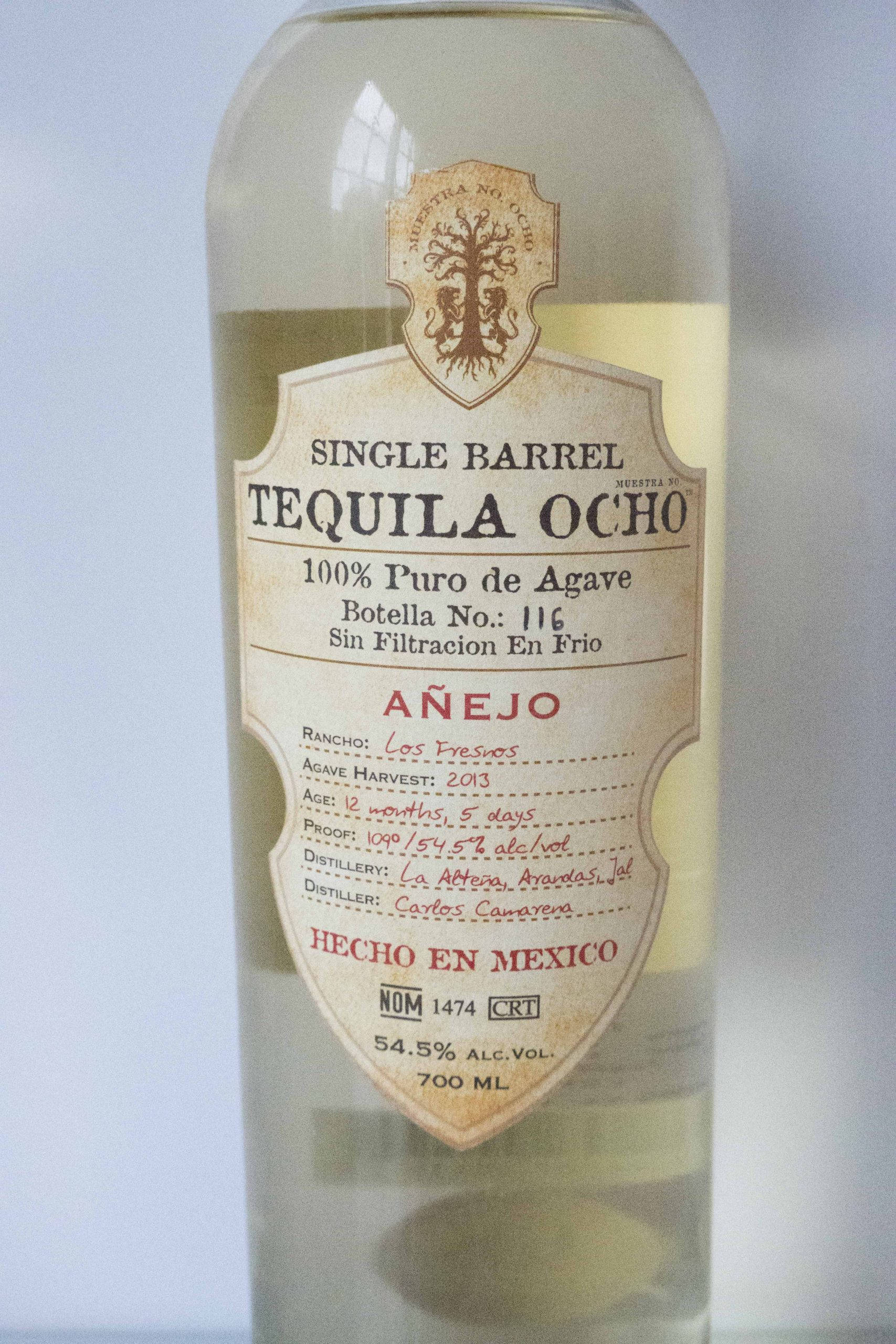 Tequila Ocho 莊園 巴巴多斯朗姆桶陳年龍舌蘭酒 壁紙 — 一個透明玻璃瓶的Single Barrel Tequila Ocho Añejo，帶有詳細的復古風格標籤，顯示墨西哥龍舌蘭產地和54.5%酒精含量。
