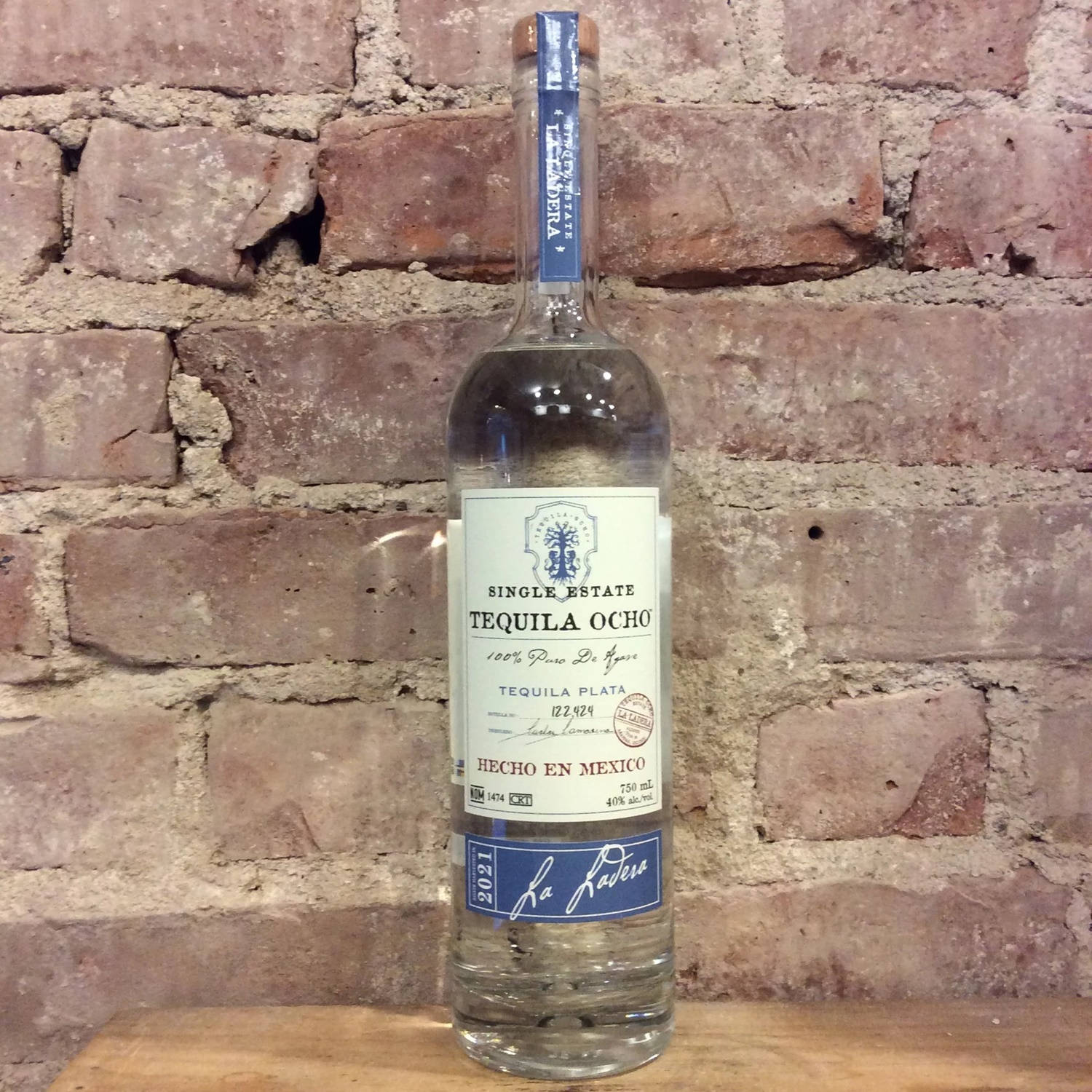 木頭上的Tequila Ocho酒瓶與磚牆。