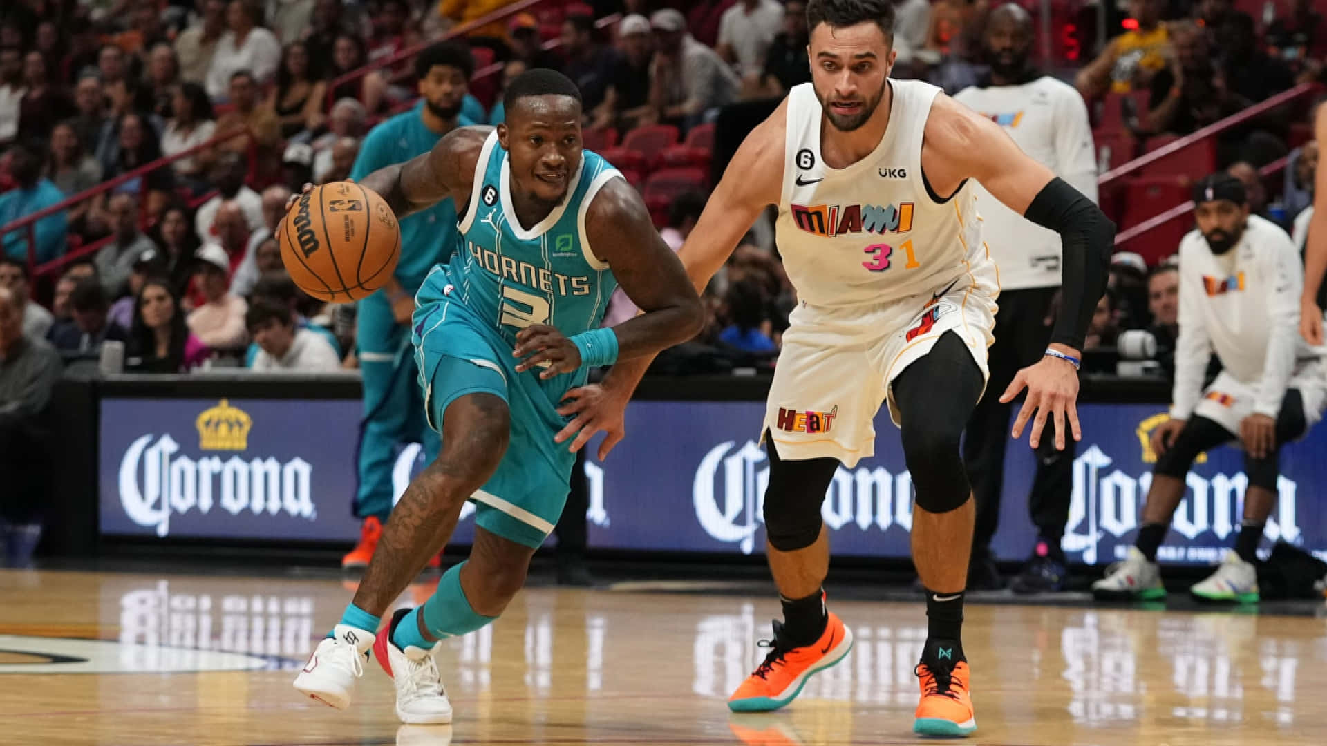 Terry Rozier 夏洛特黃蜂隊突破 壁紙 — 一名身穿青綠色球衣的籃球運動員在場館燈光下的一場激烈比賽中，運球越過一名身穿白色球衣的防守球員。