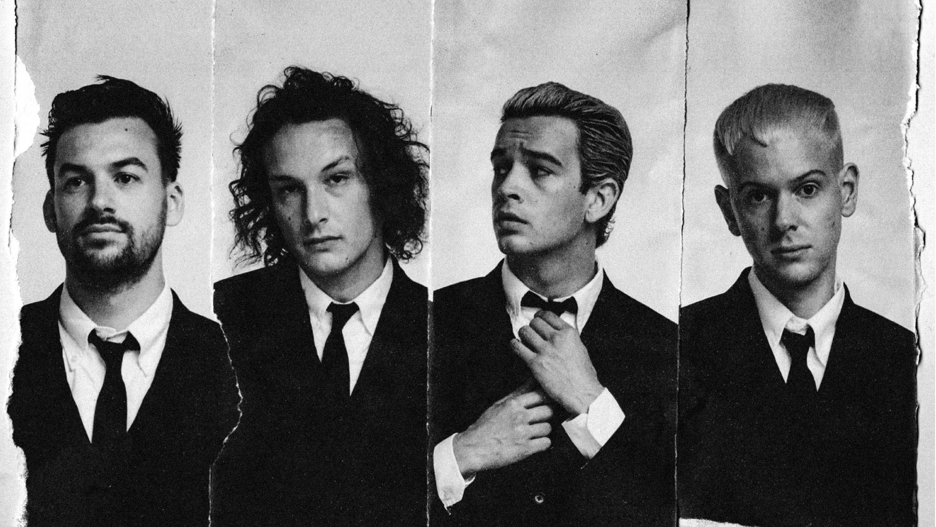 The 1975 乐队成員 壁紙 — 四個穿著西裝的男人從撕裂的黑白肖像條中強烈凝視，背景樸素。