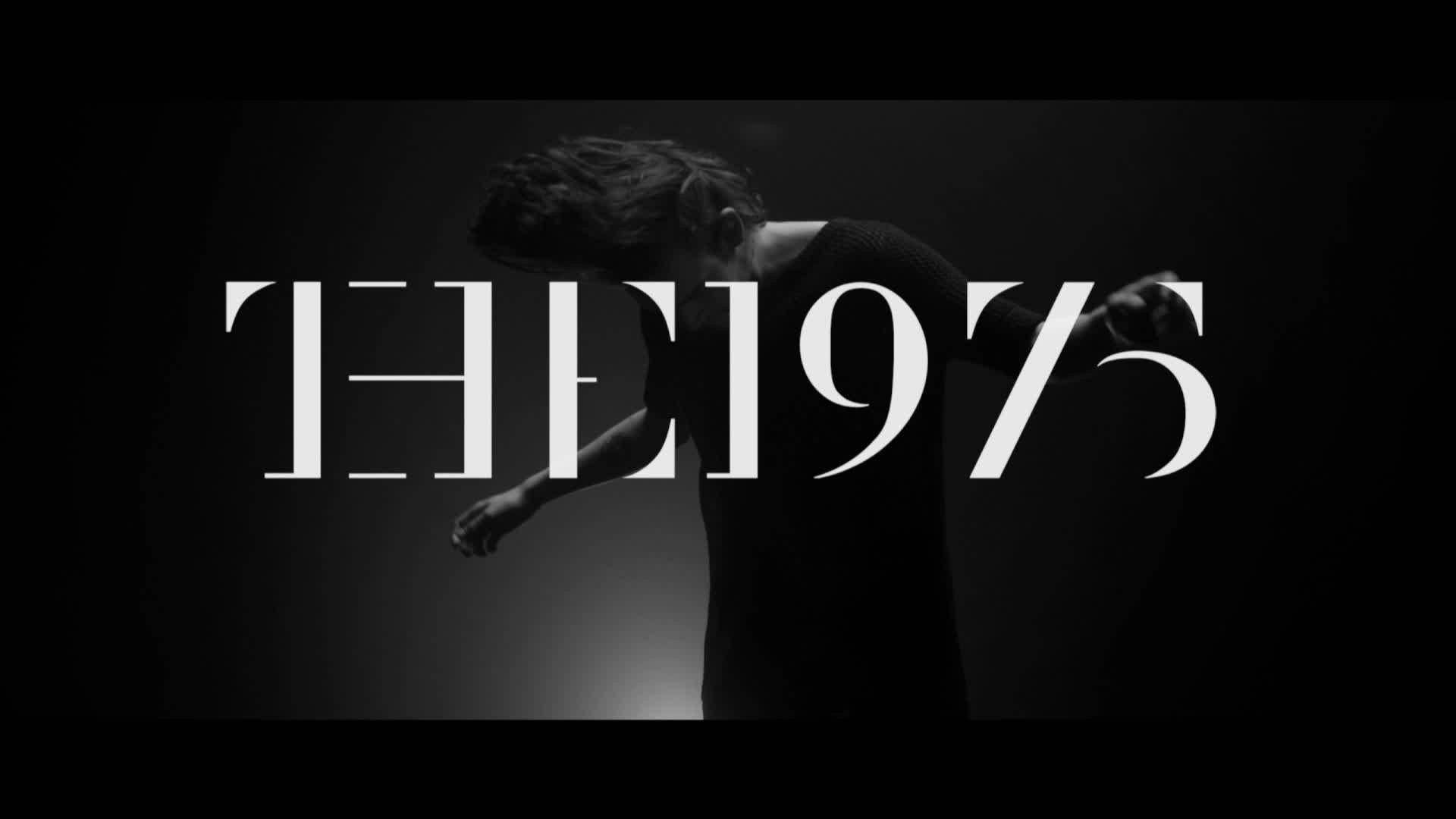 The 1975 標誌狂野風 壁紙 — 一個正在移動的人物單色剪影，在深色漸變背景上帶有粗體白色文字 'THE 1975'。