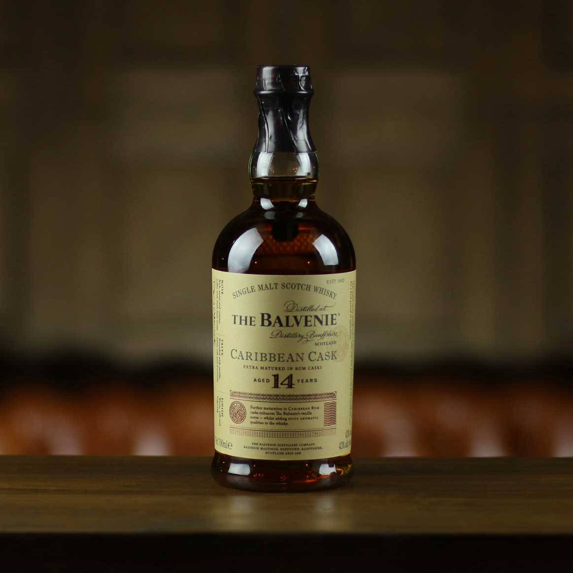 一瓶 The Balvenie 14 年 Caribbean Cask 威士忌放在木桌上。
