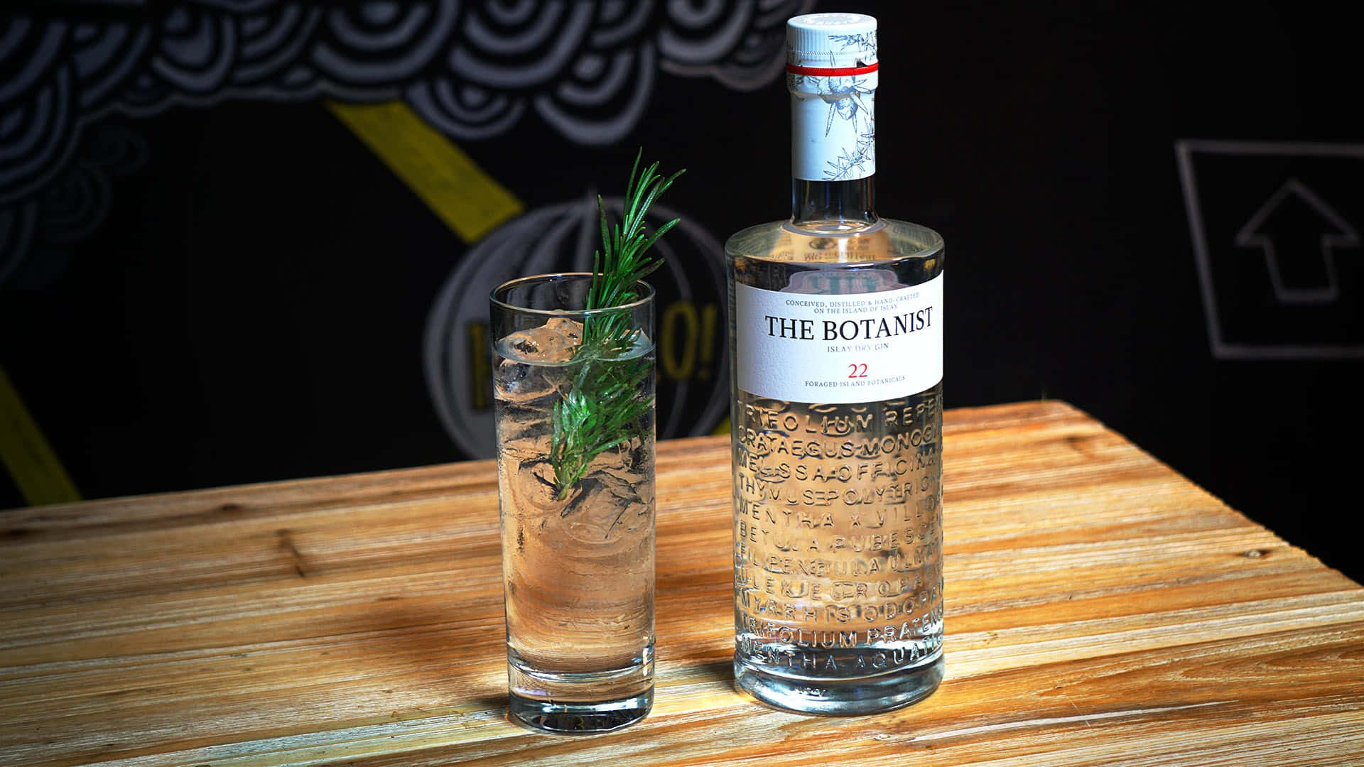 Botanist 氈酒瓶和迷迭香雞尾酒在木桌上。