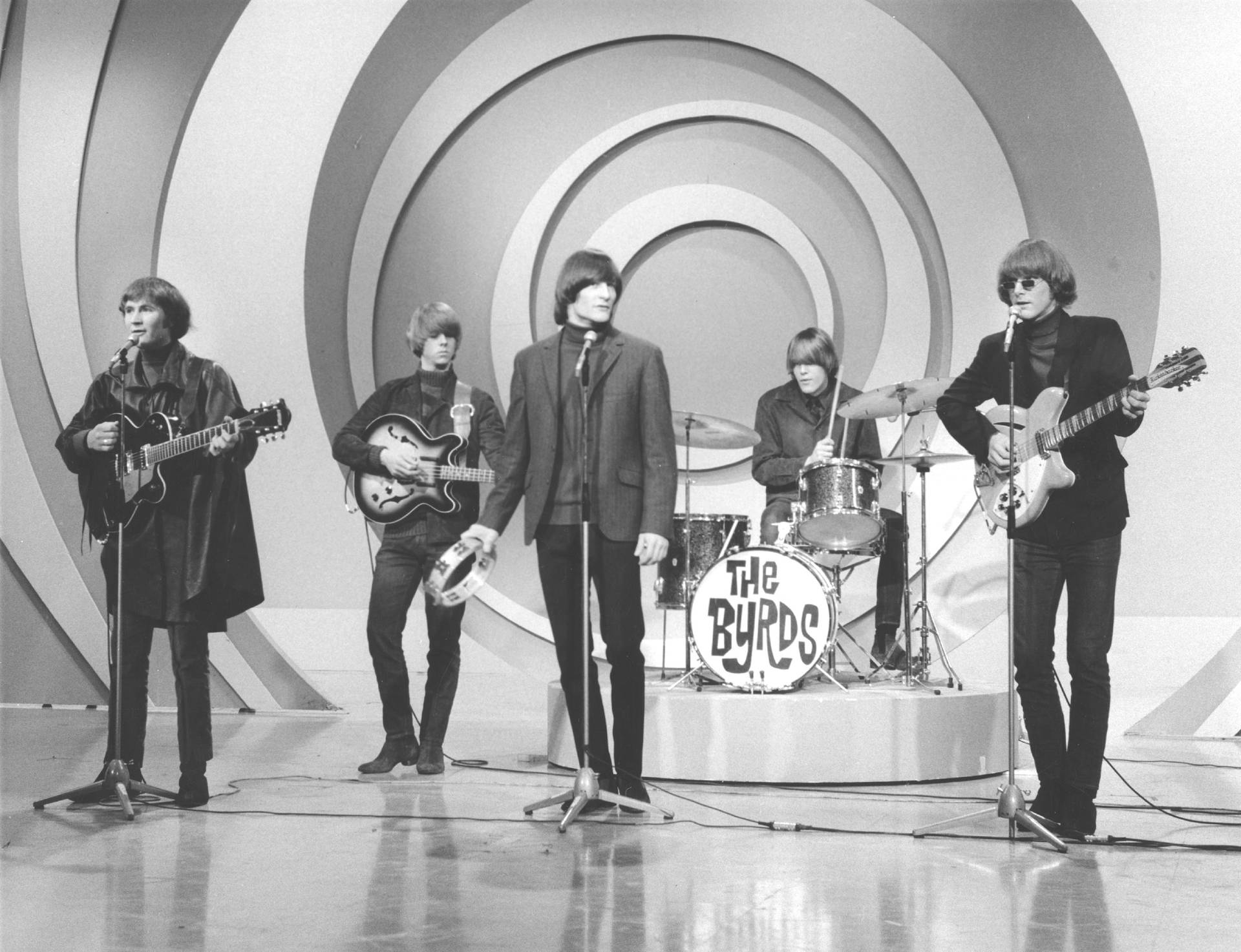 The Byrds 在螺旋背景前現場演奏結他和鼓。