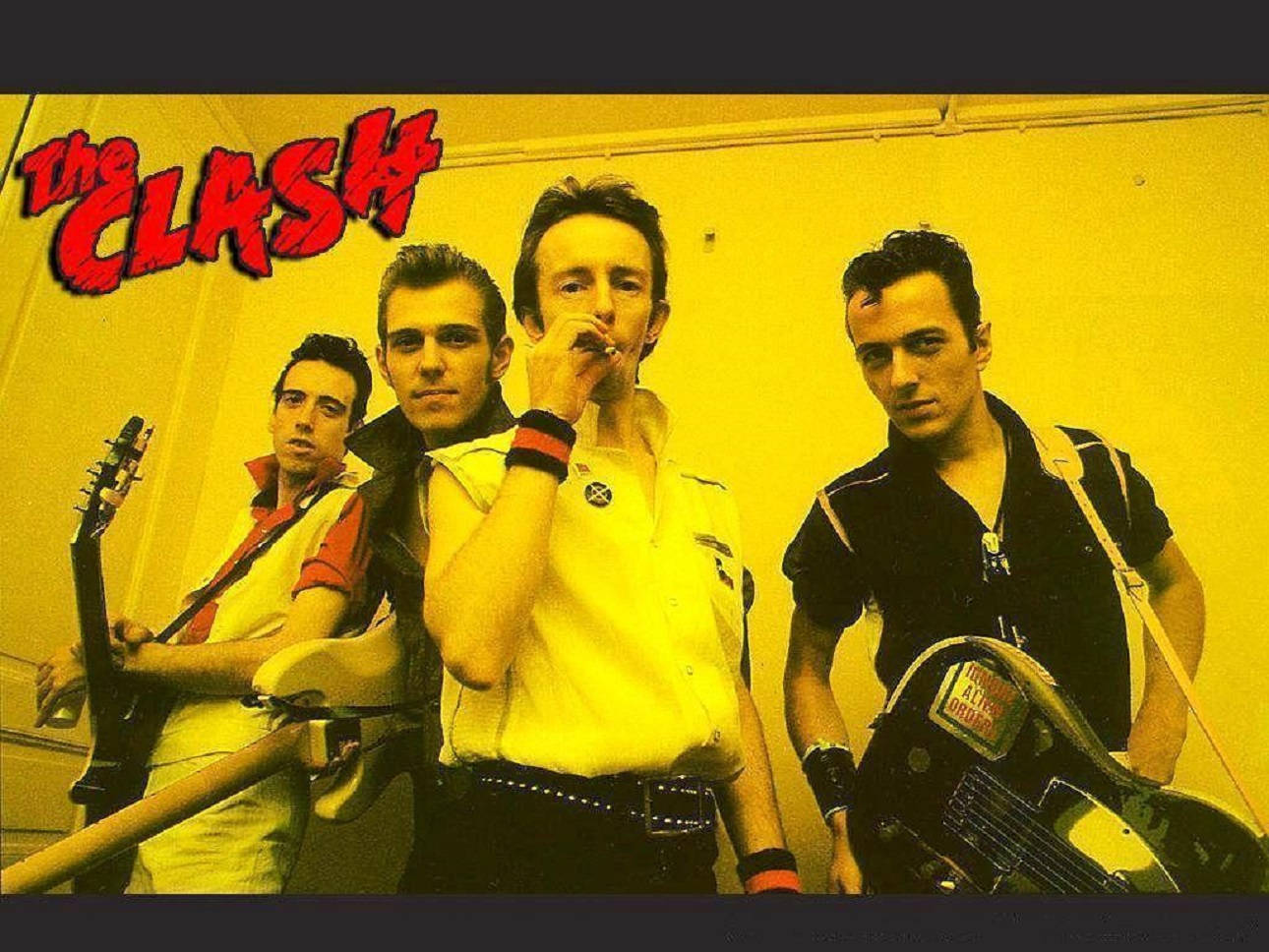 龐克搖滾樂隊 The Clash 在黃色房間裡拿著結他擺姿勢。