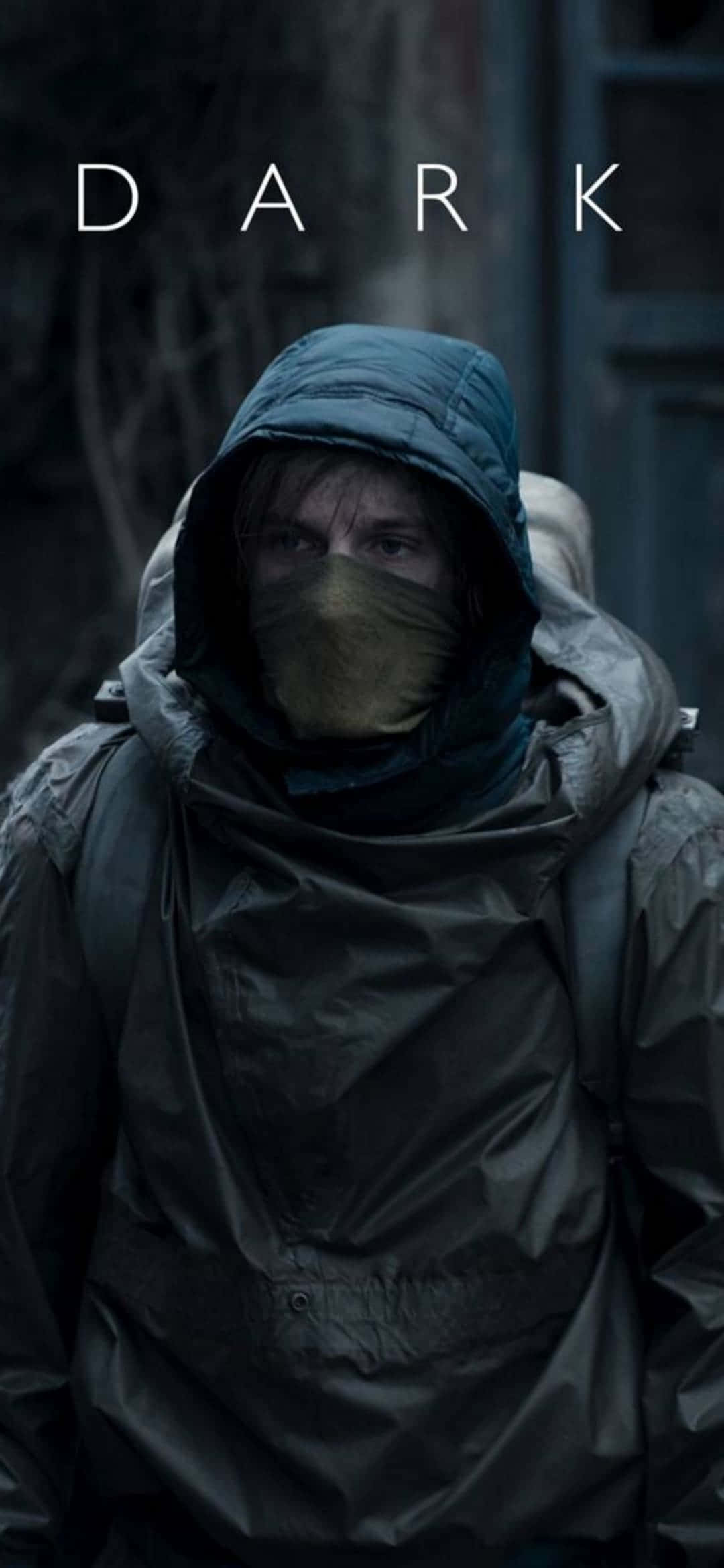 《The Dark》Netflix 原創劇集 iPhone 壁紙 — 一個穿著深色連帽雨衣和口罩的人站在昏暗燈光下的陰暗城市小巷中。
