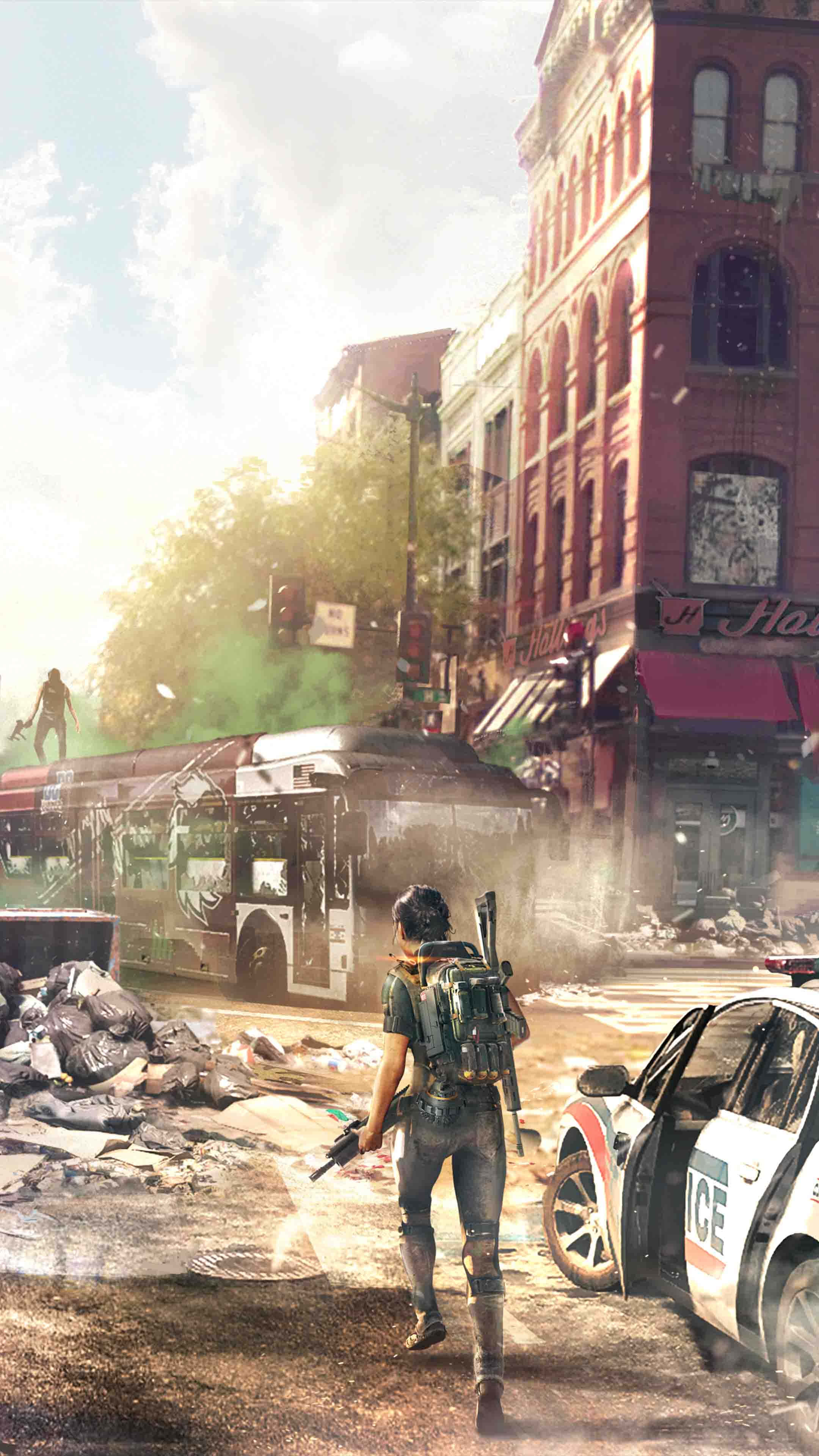 《The Division》安卓背景：戰鬥場景 壁紙 — 一個孤獨的倖存者走過陽光明媚、瓦礫遍佈的城市街道，經過一輛被毀壞的巴士和警車。