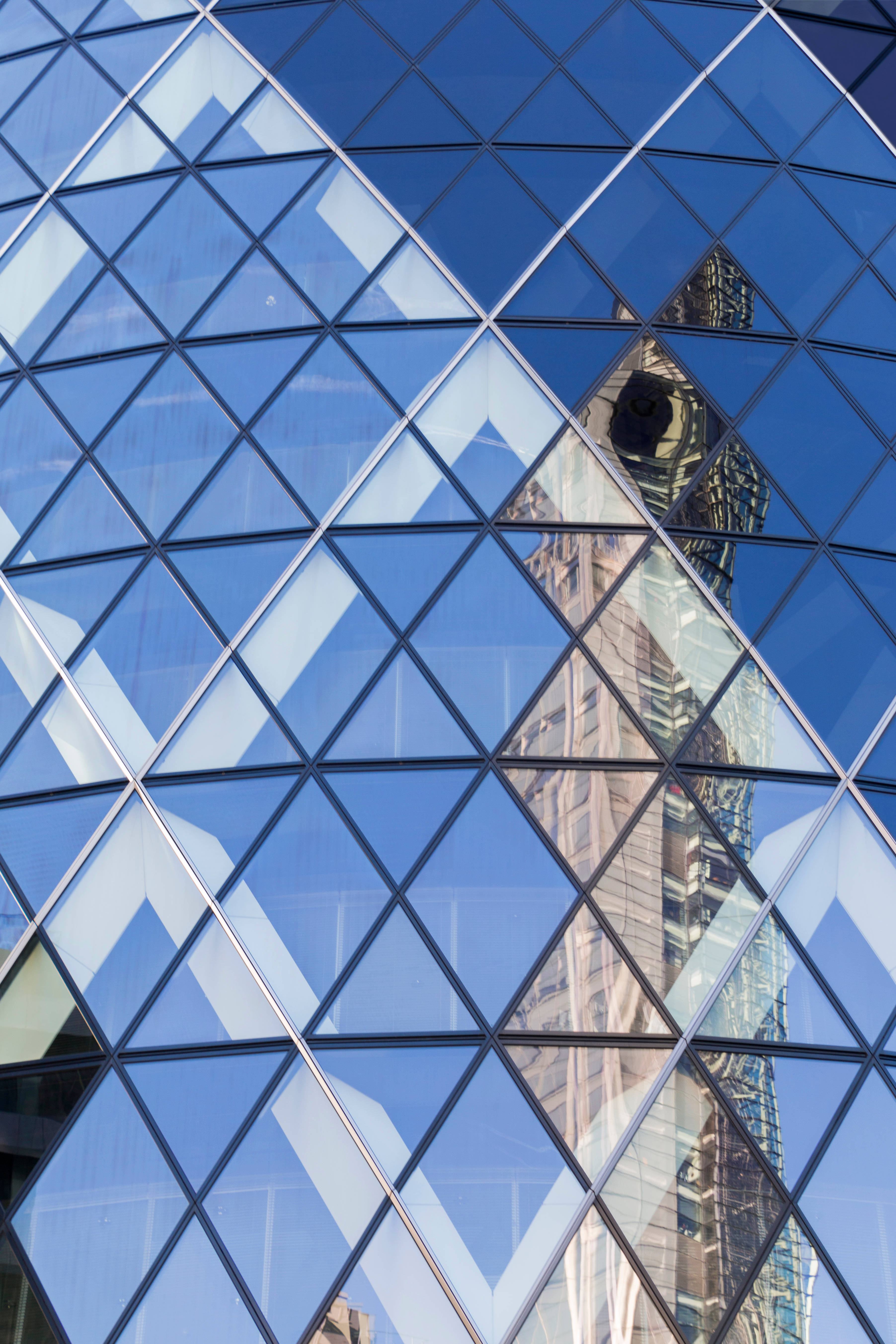 The Gherkin 玻璃窗特寫 壁紙 — 現代玻璃摩天大樓鑽石圖案外牆的特寫，反射鄰近建築物和藍天。