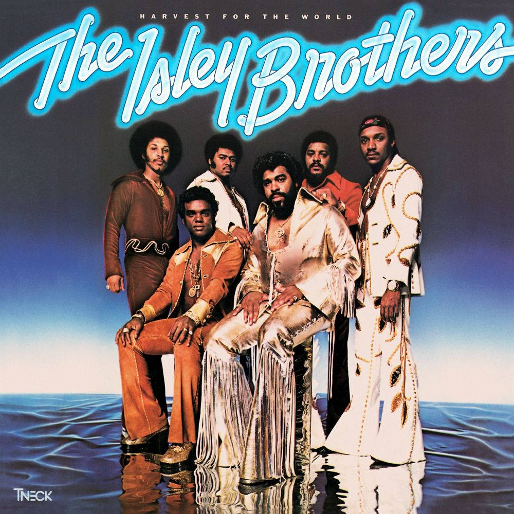 The Isley Brothers《Harvest For The World》專輯封面 壁紙 — The Isley Brothers 穿著華麗的70年代服裝，站在水上，背景是漸變天空，上方有發光的藍色文字。