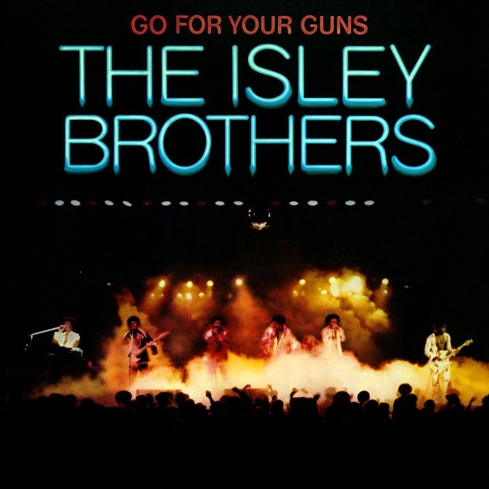 The Isley Brothers《Go For Your Guns》專輯封面 壁紙 — The Isley Brothers 在煙霧瀰漫的舞台上表演，舞台被熾熱的橙色燈光籠罩，下方是發光的霓虹文字。