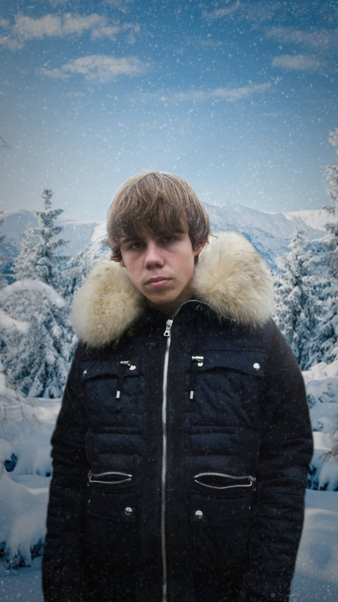 年輕男子穿著冬季外套站在雪地山林中